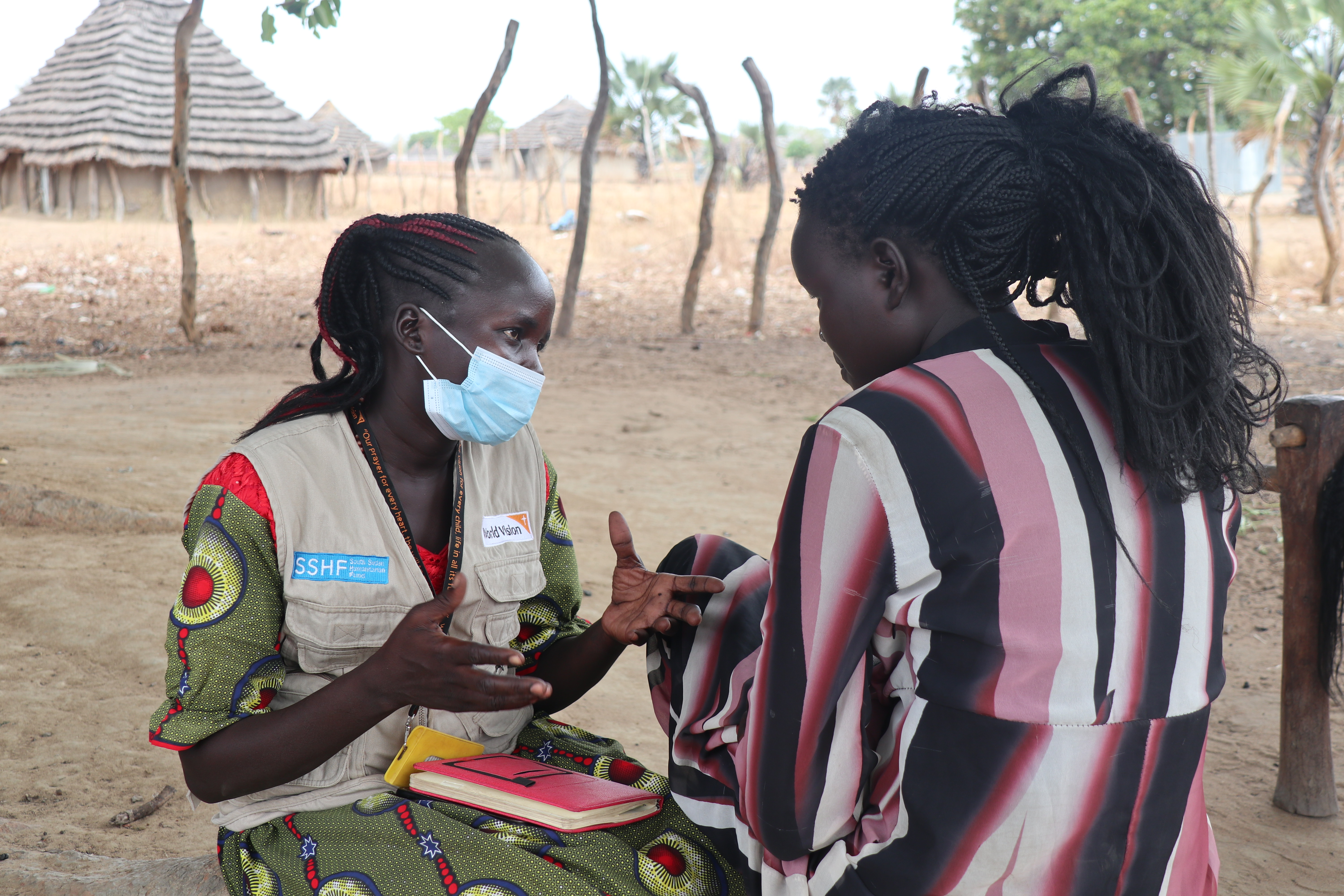 World Vision volunteer Pasquina talking to beneficiary Katina