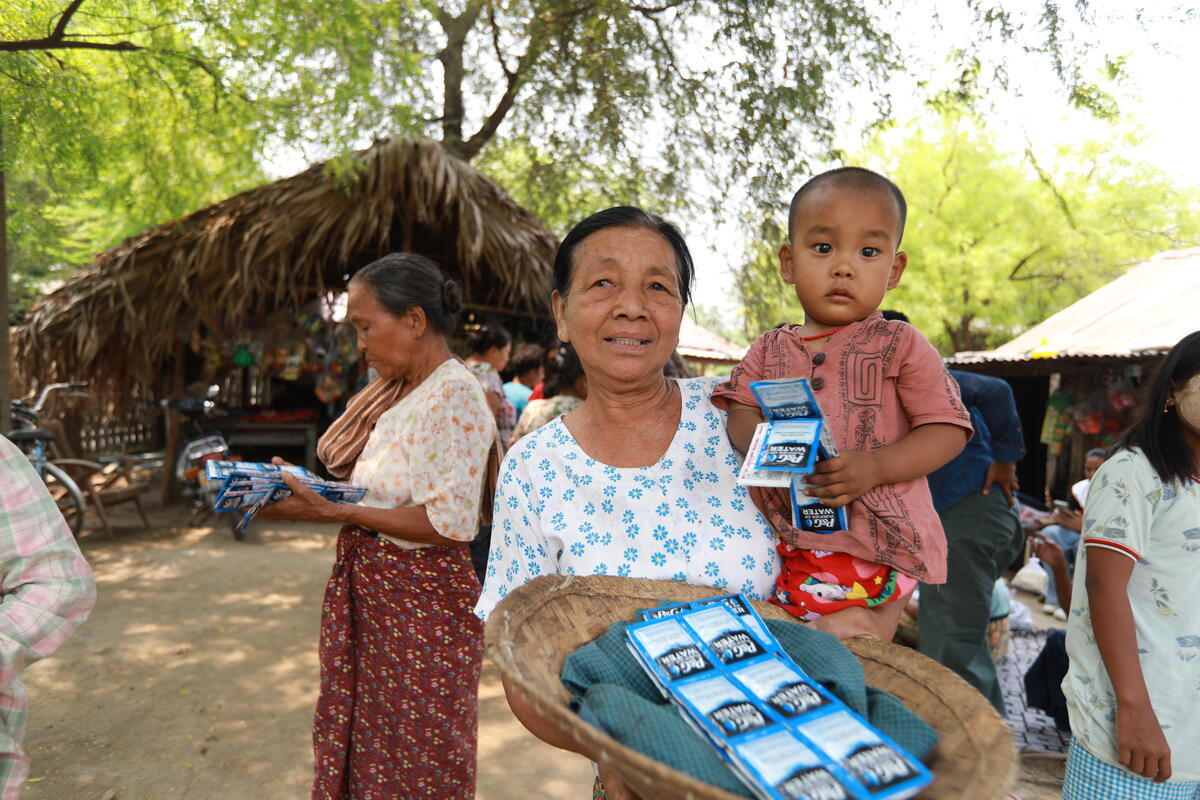 A grandmother holds her grandchild with a row of hygeine products