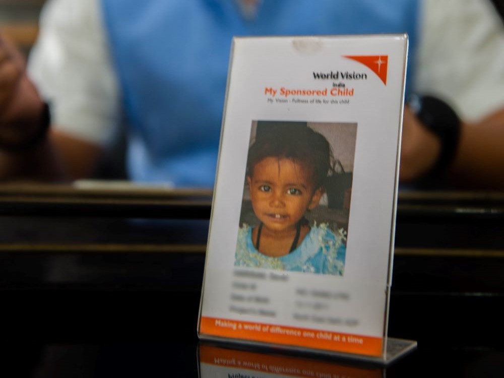 Neeraj with photo of the child he sponsors