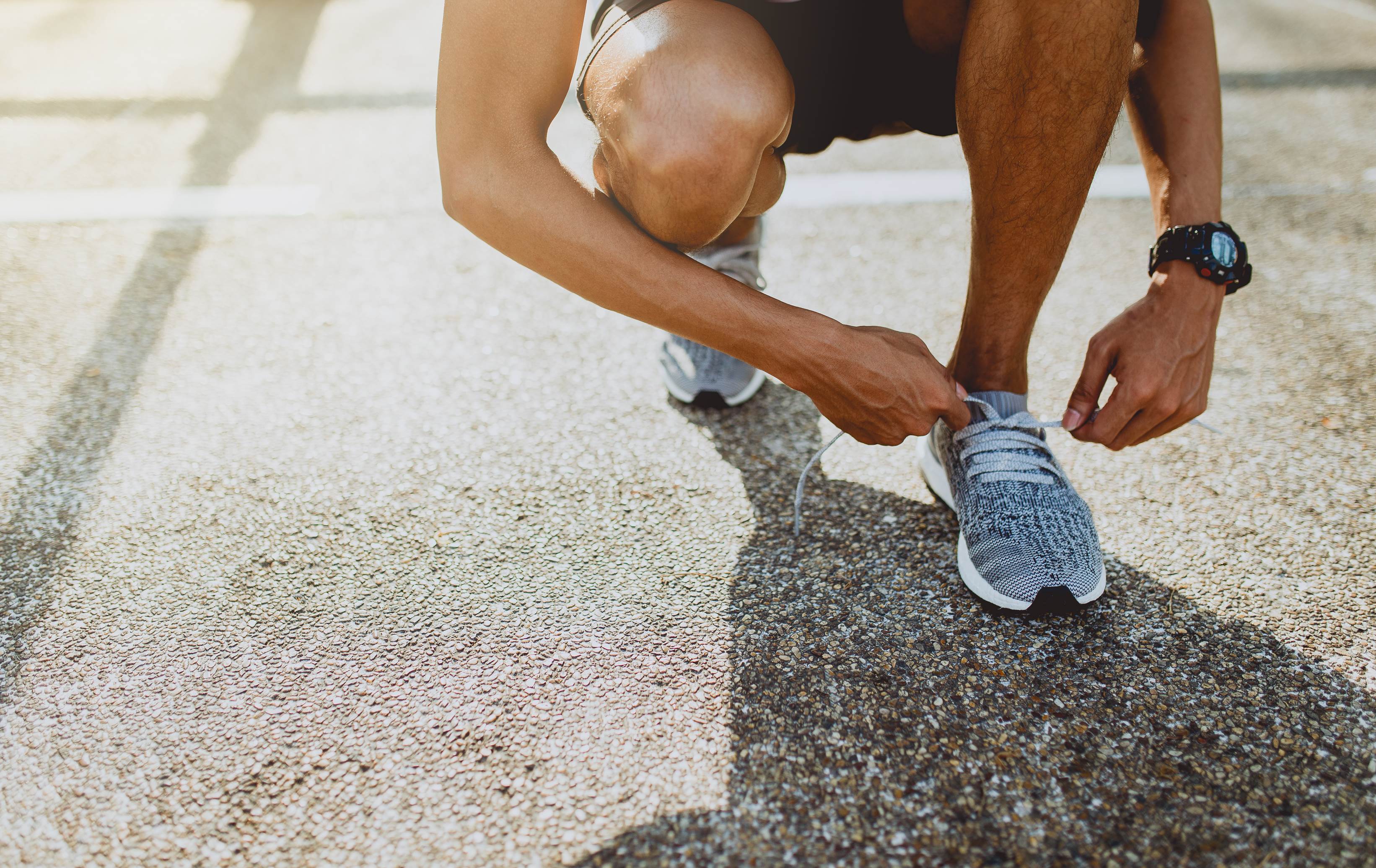 A person tying their running shoes outdoors
