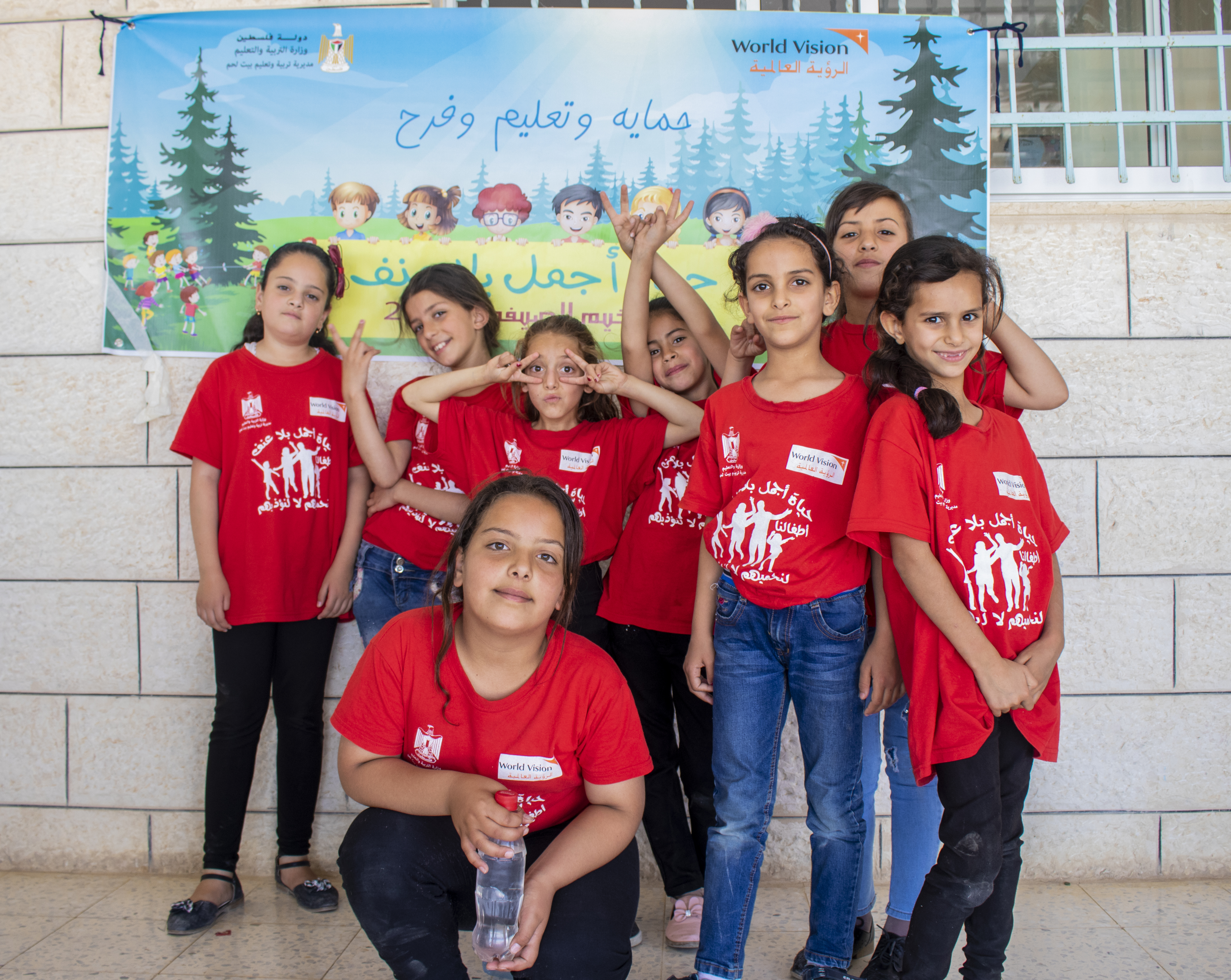 A group of girls in red t-shirts pose together in front of a wall