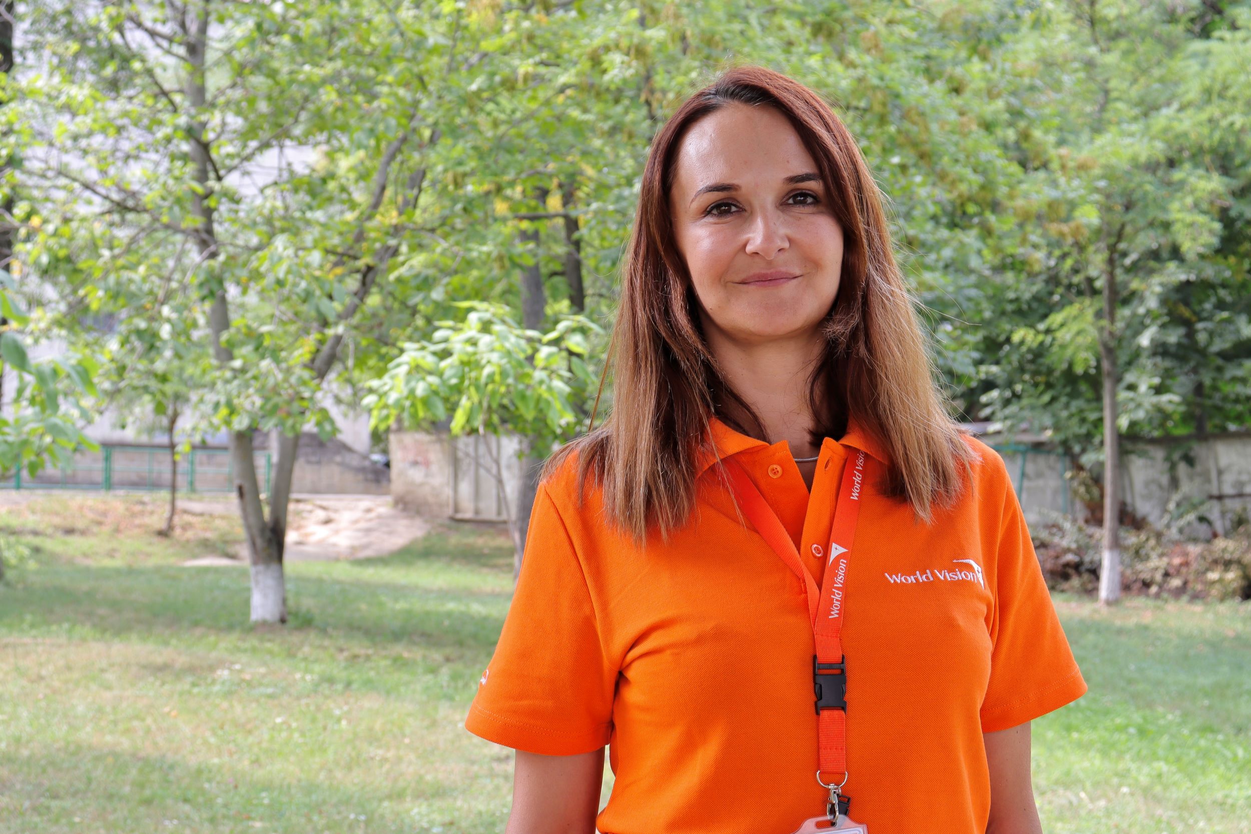 World Vision worker smiling in orange t-shirt