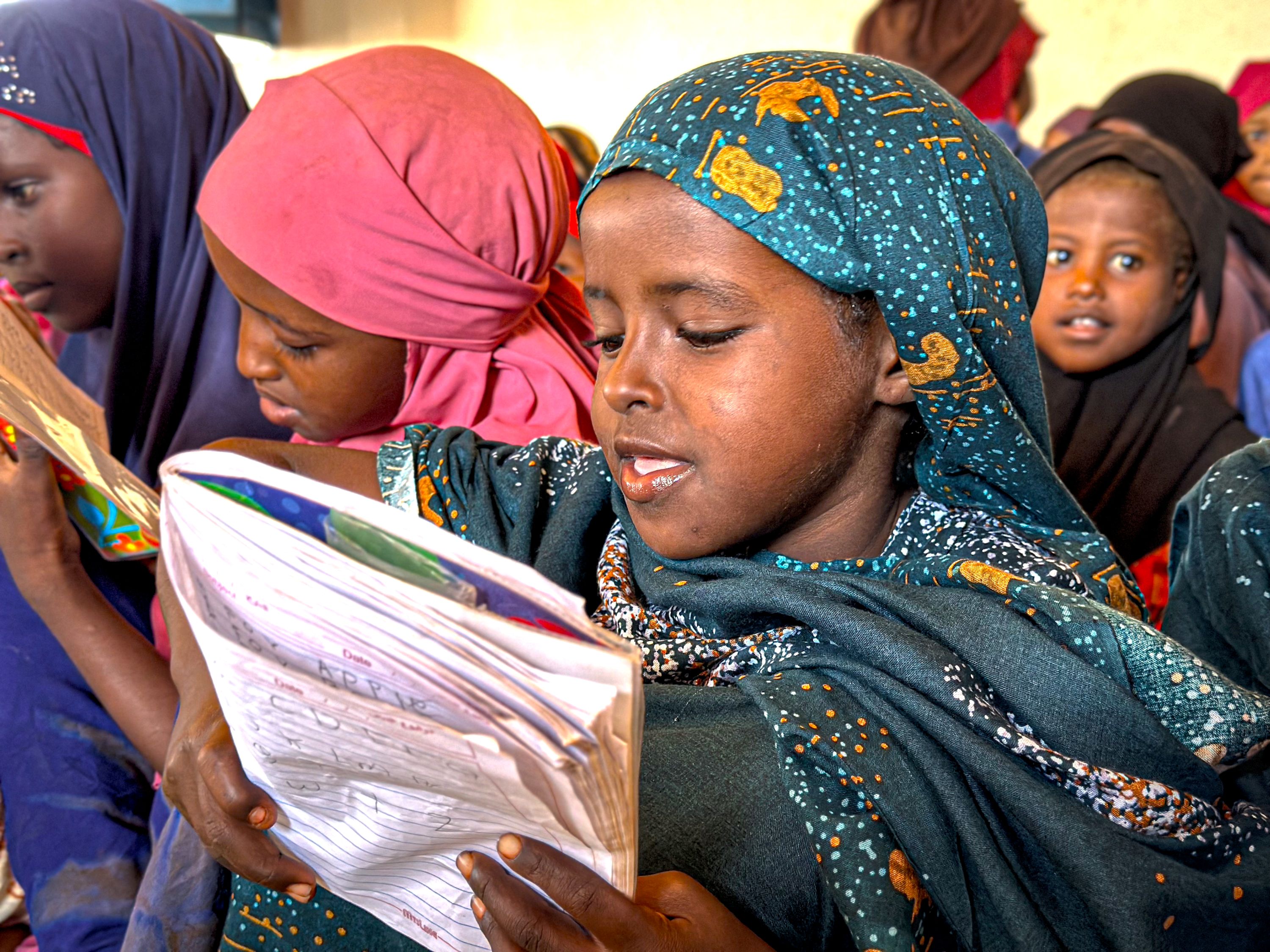 Children like Sucdi, pictured among a group of children, are learning to read and write at a Child Friendly Space