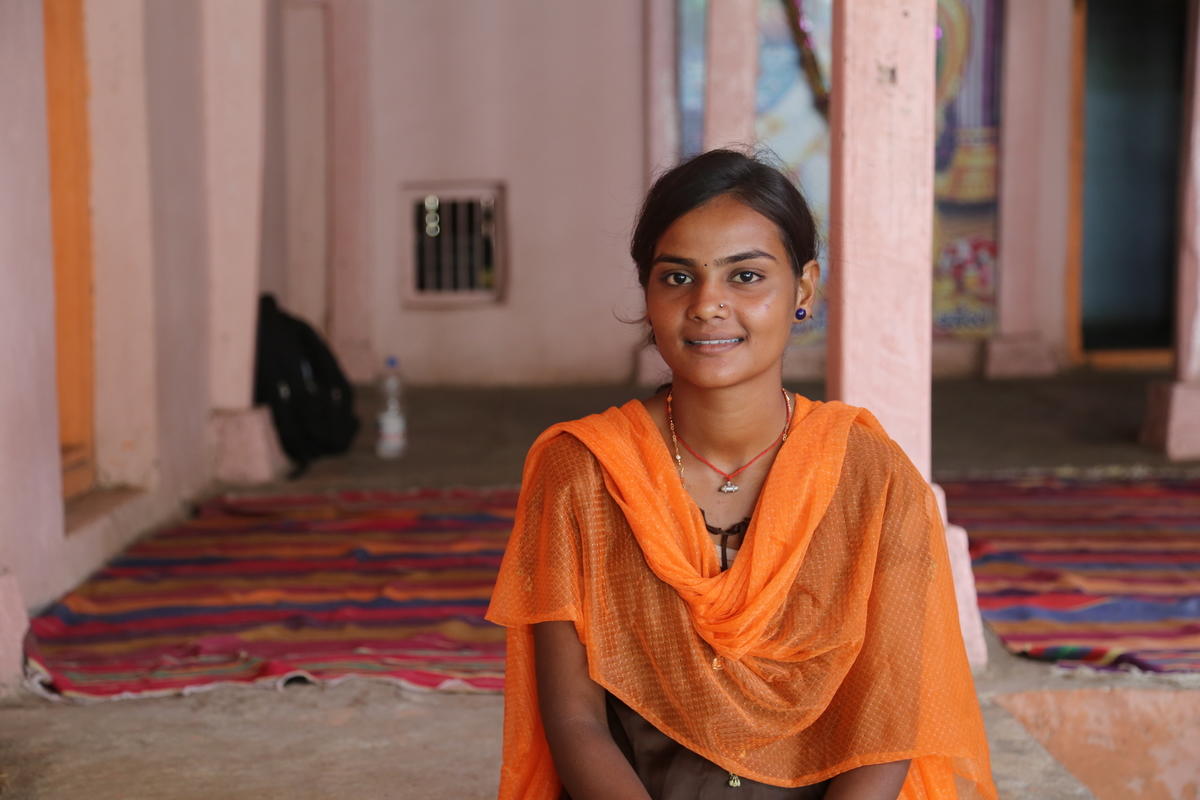 Sponsored child from India smiles as she wears an orange dress