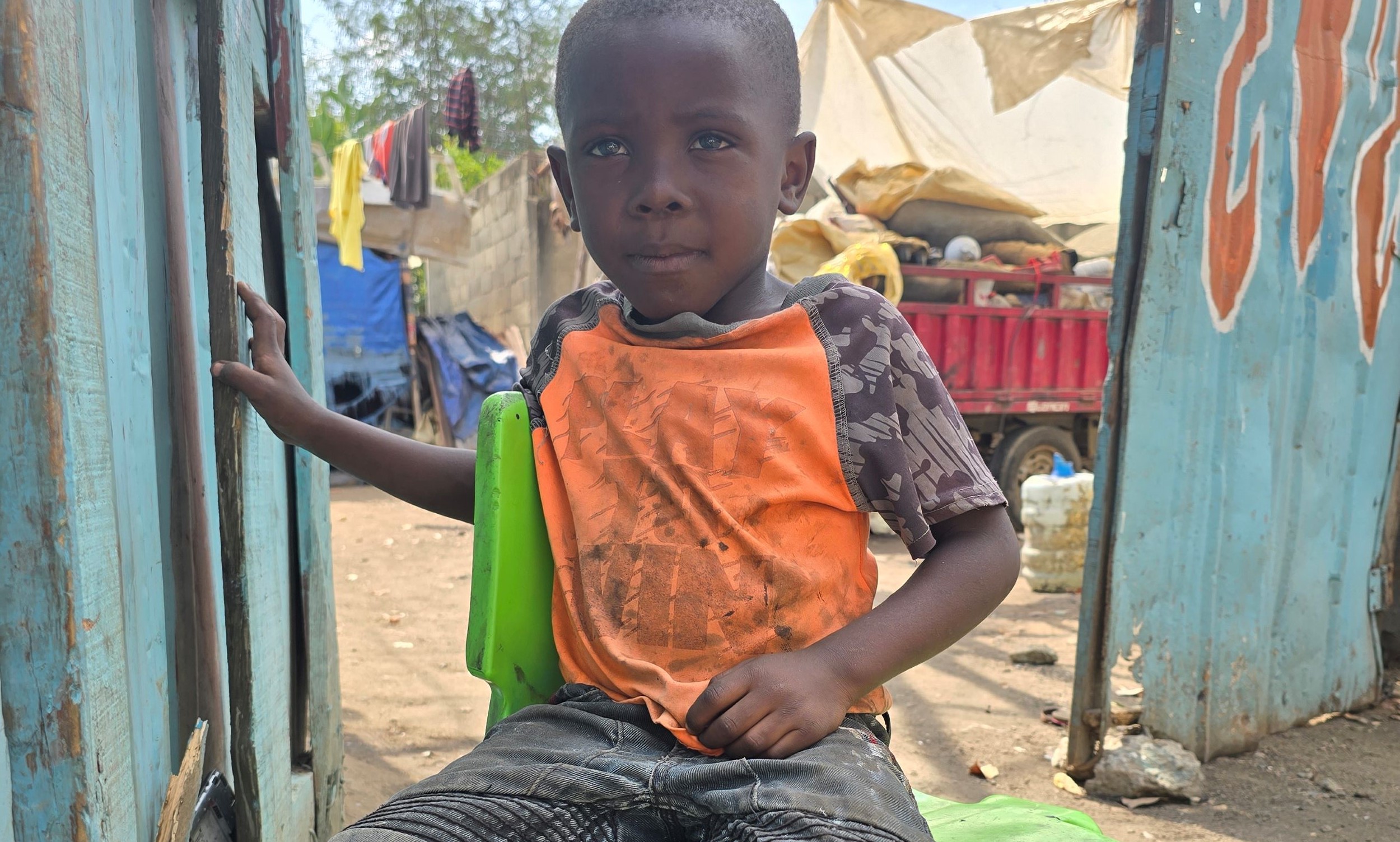 Sitting on a green plastic chair, five-year-old Jair has recently fled Haiti for the Dominican Republic