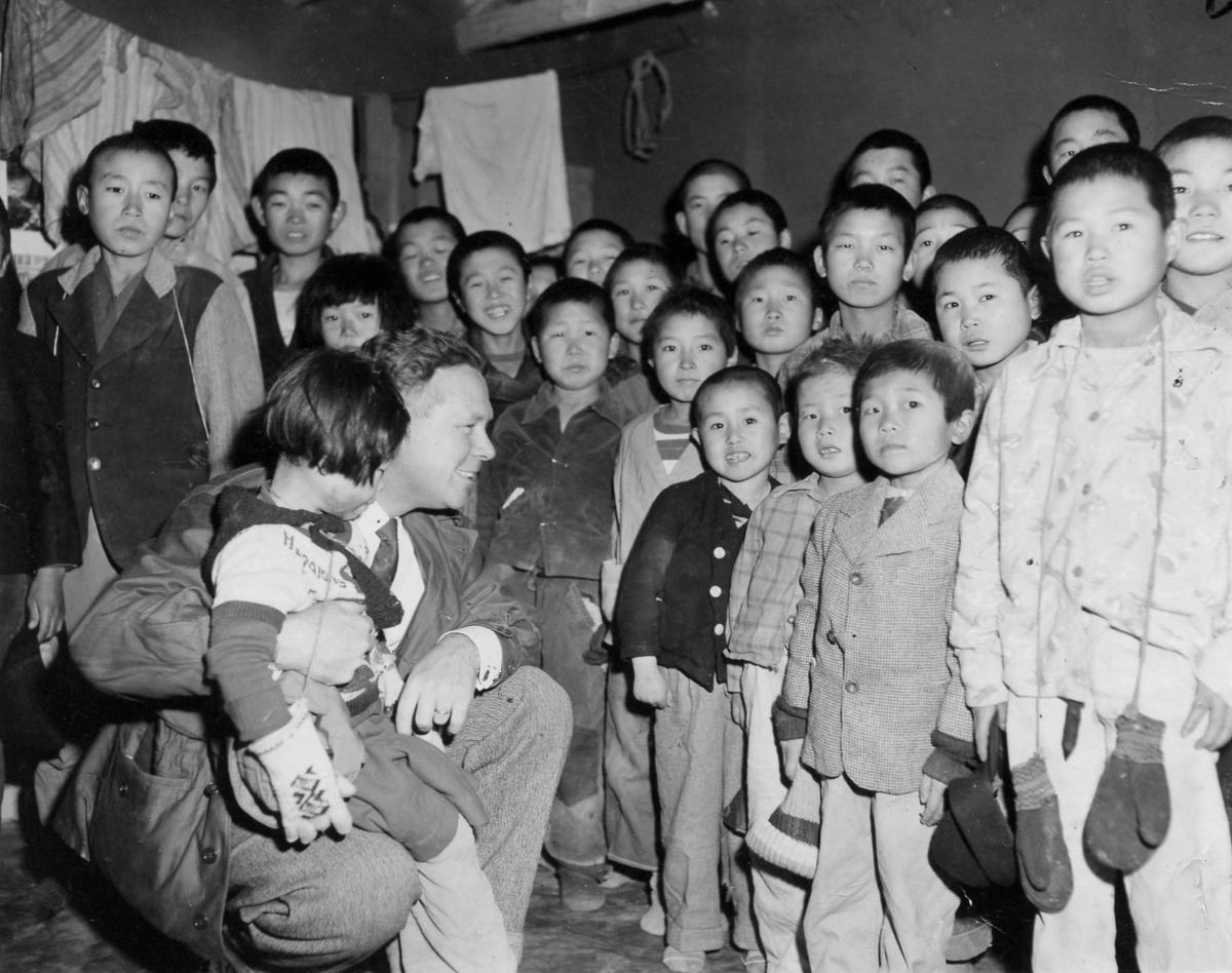 Bob Pierce, World Vision founder, stands with a large group of young children