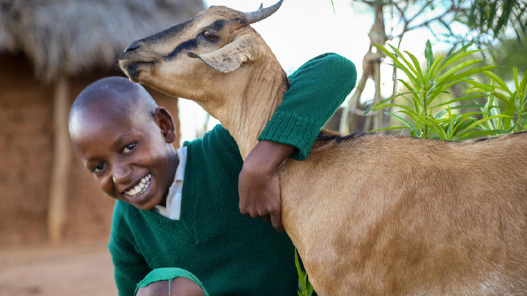 Joseph, in Kenya, hugs his family's goat.