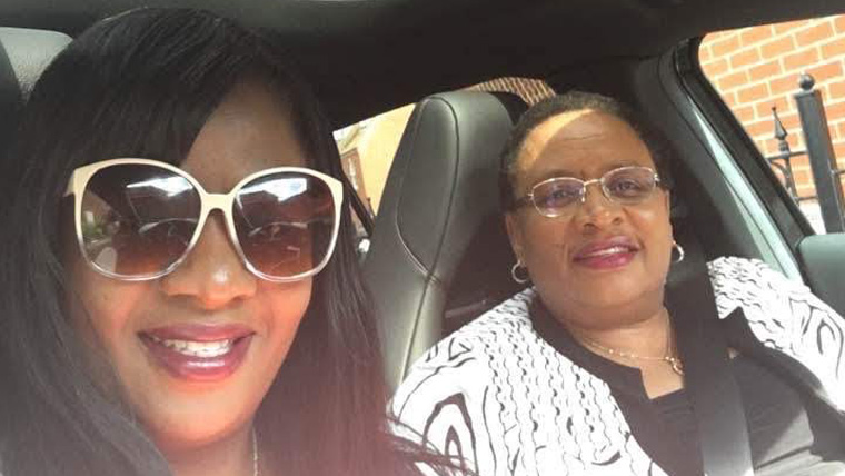 Two UK women, one wearing sunglasses, sit in a car and smile as they take a selfie