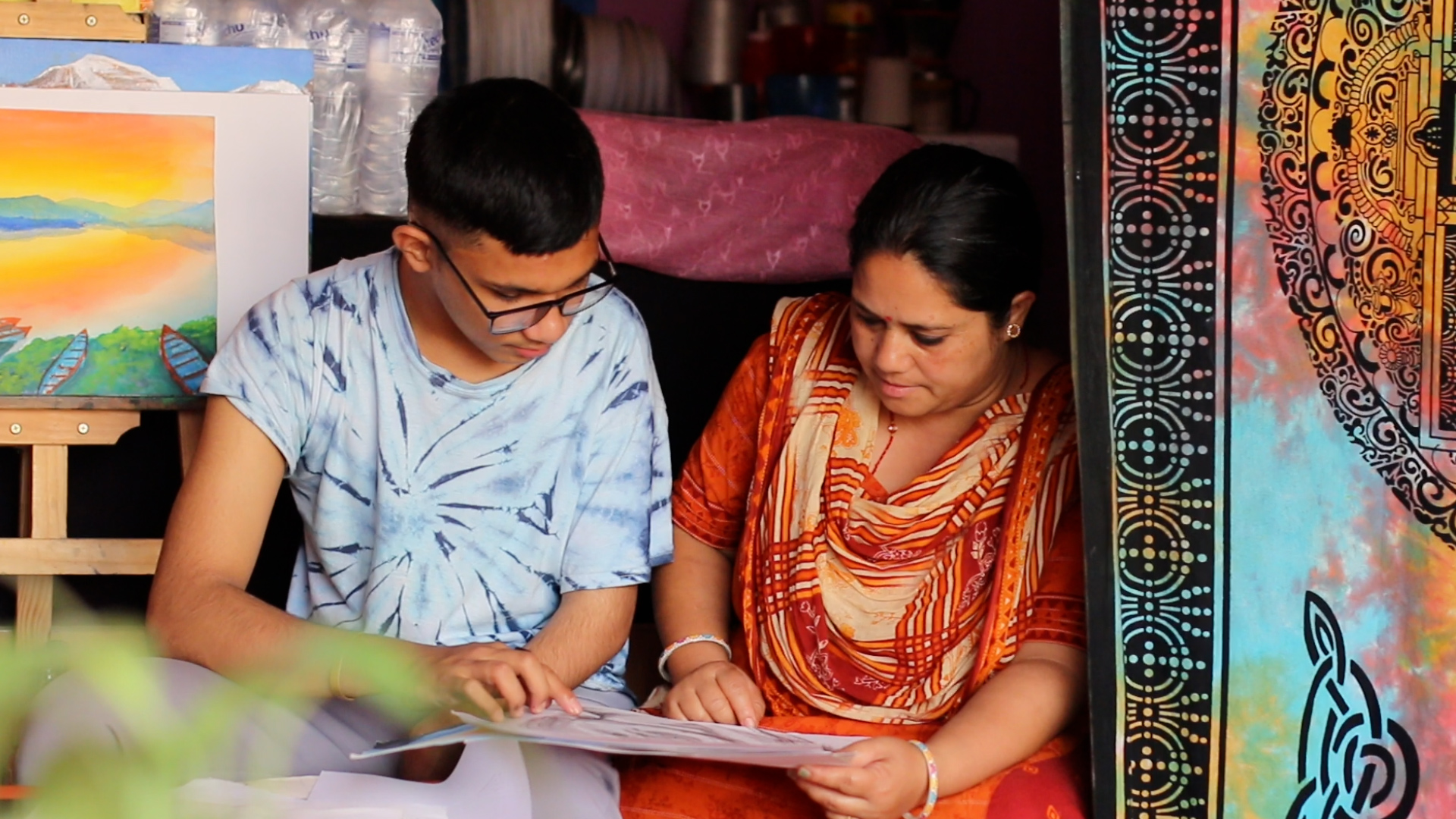 Nepali mother and son looking at his drawing
