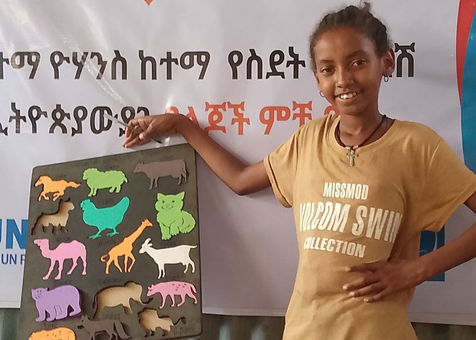 A smiling Tsion, 9, displaying her creation at the Child Friendly Space where she has grown in confidence and made friends