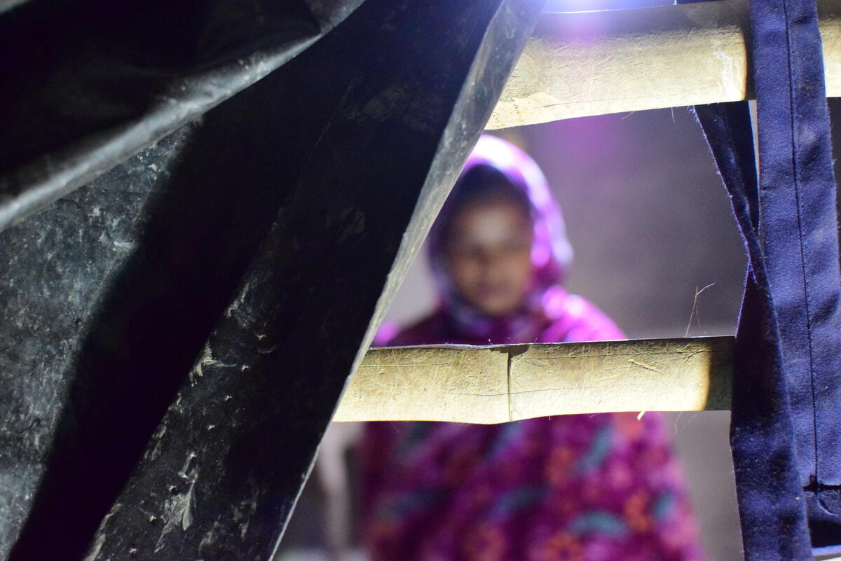 Unfocused portrait of a girl wearing colourful headscarf sat behind bamboo bars