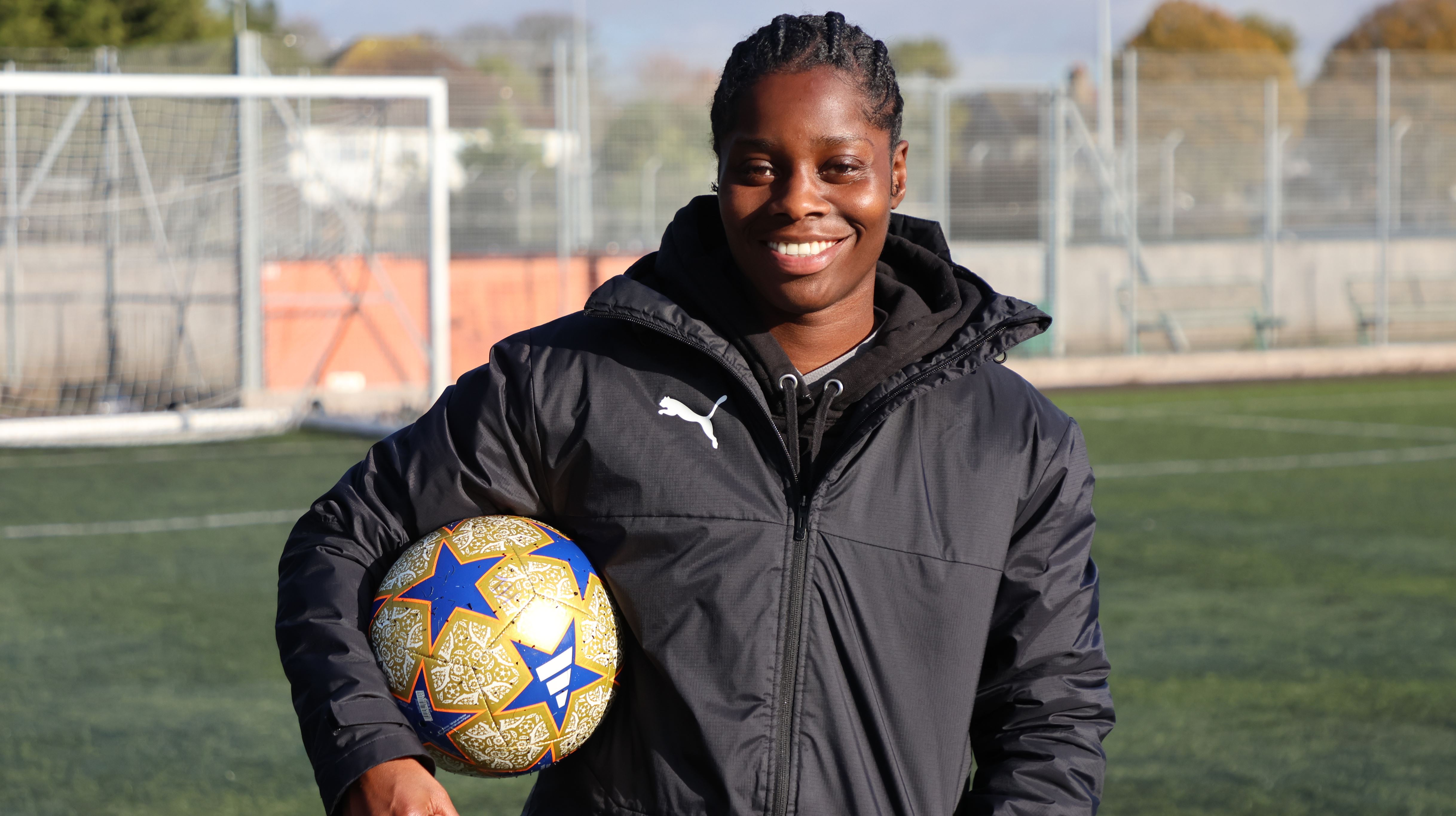 Freda smiles whilst holding a football under her arm
