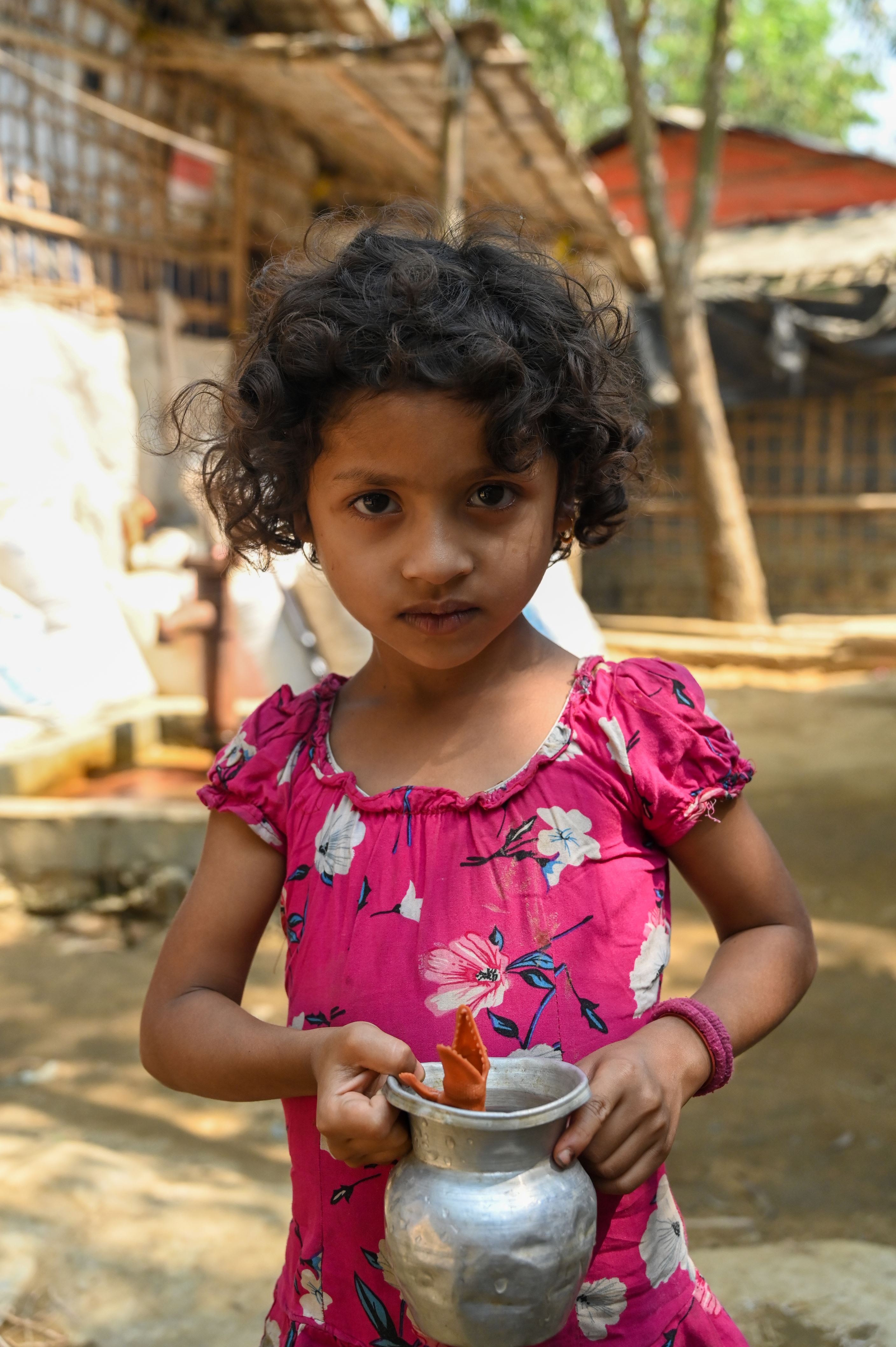 A young refugee girl holds a bottle for water in a camp in Bangladesh