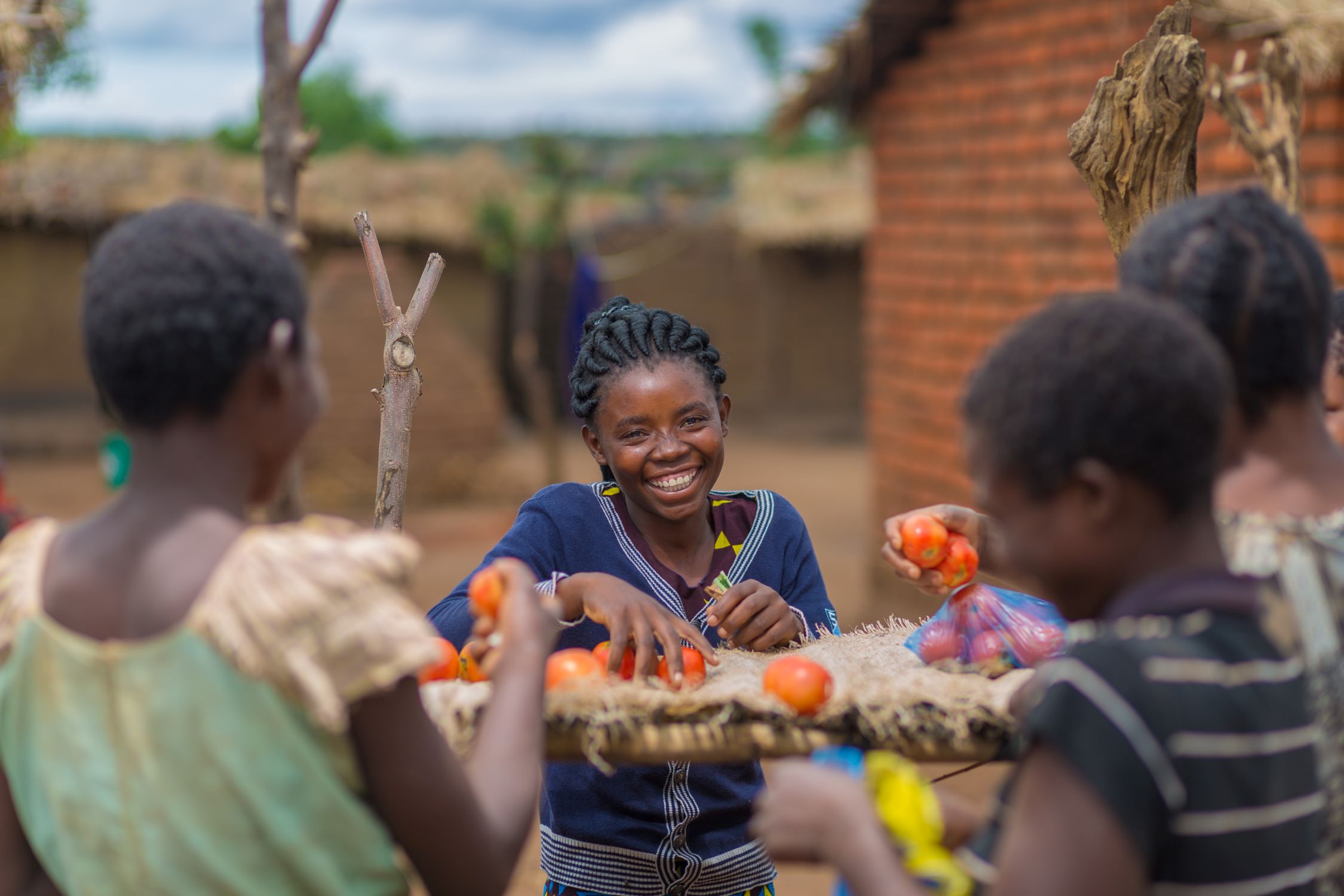 Young women from Malawi smiling around tomatoes