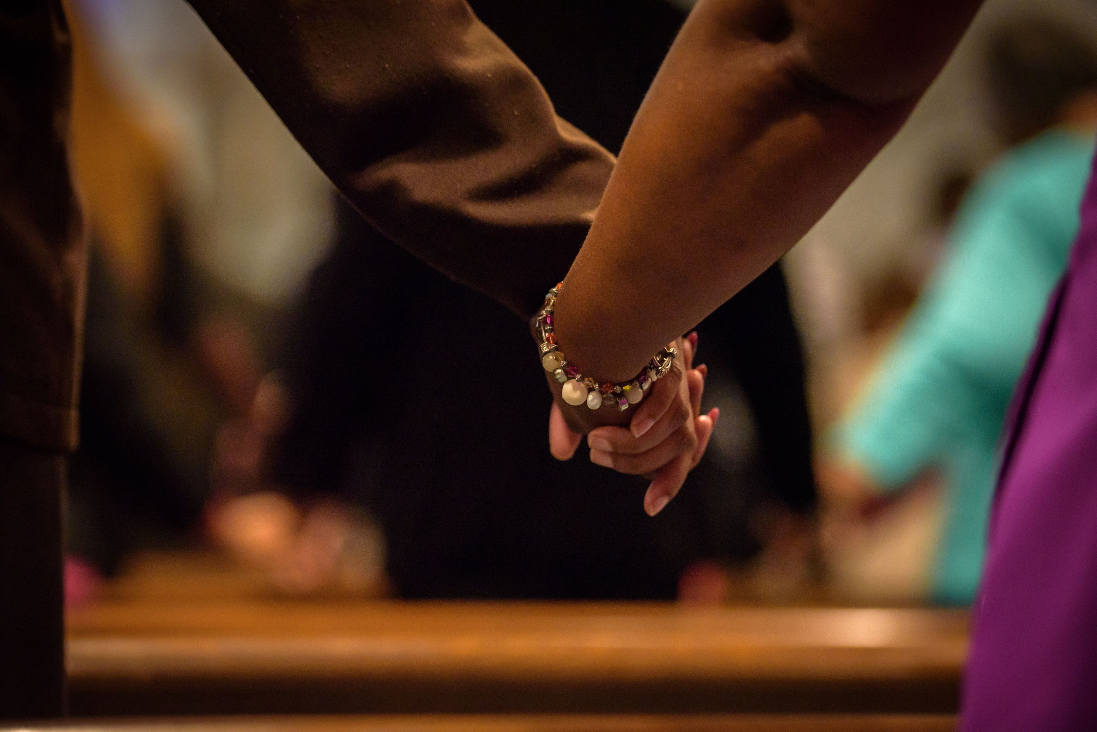 People in the USA stand with arms clasped, in front of a church pew