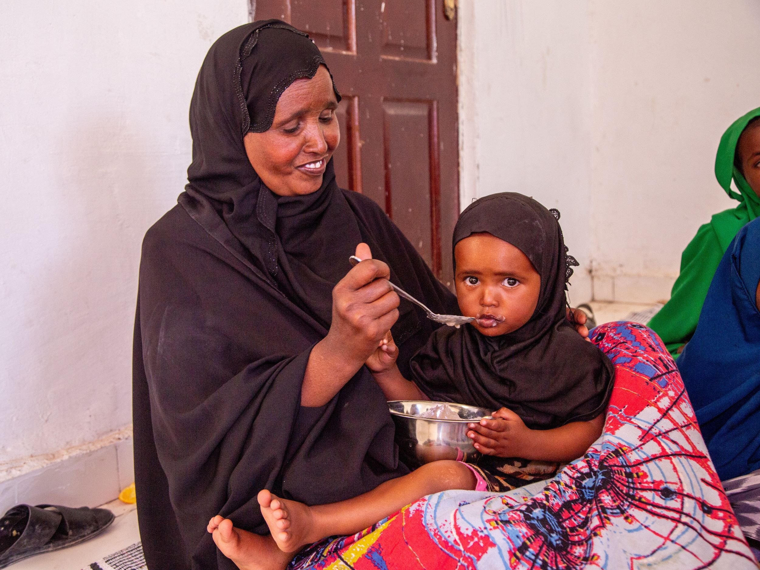 A Somali mother holding and feeding her young daughter
