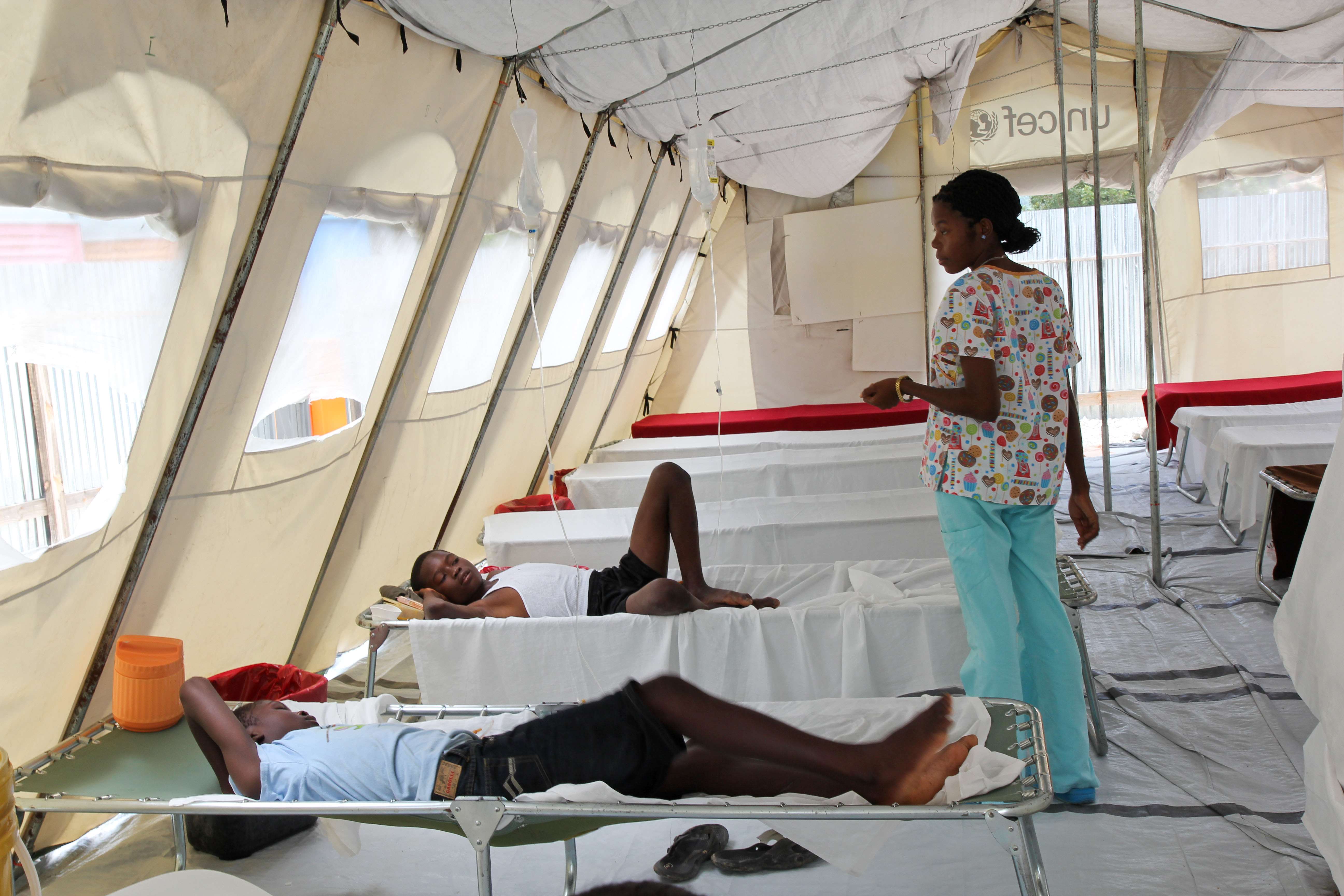 A nurse stands in the middle of a cholera tent in Haiti with patients lying on beds