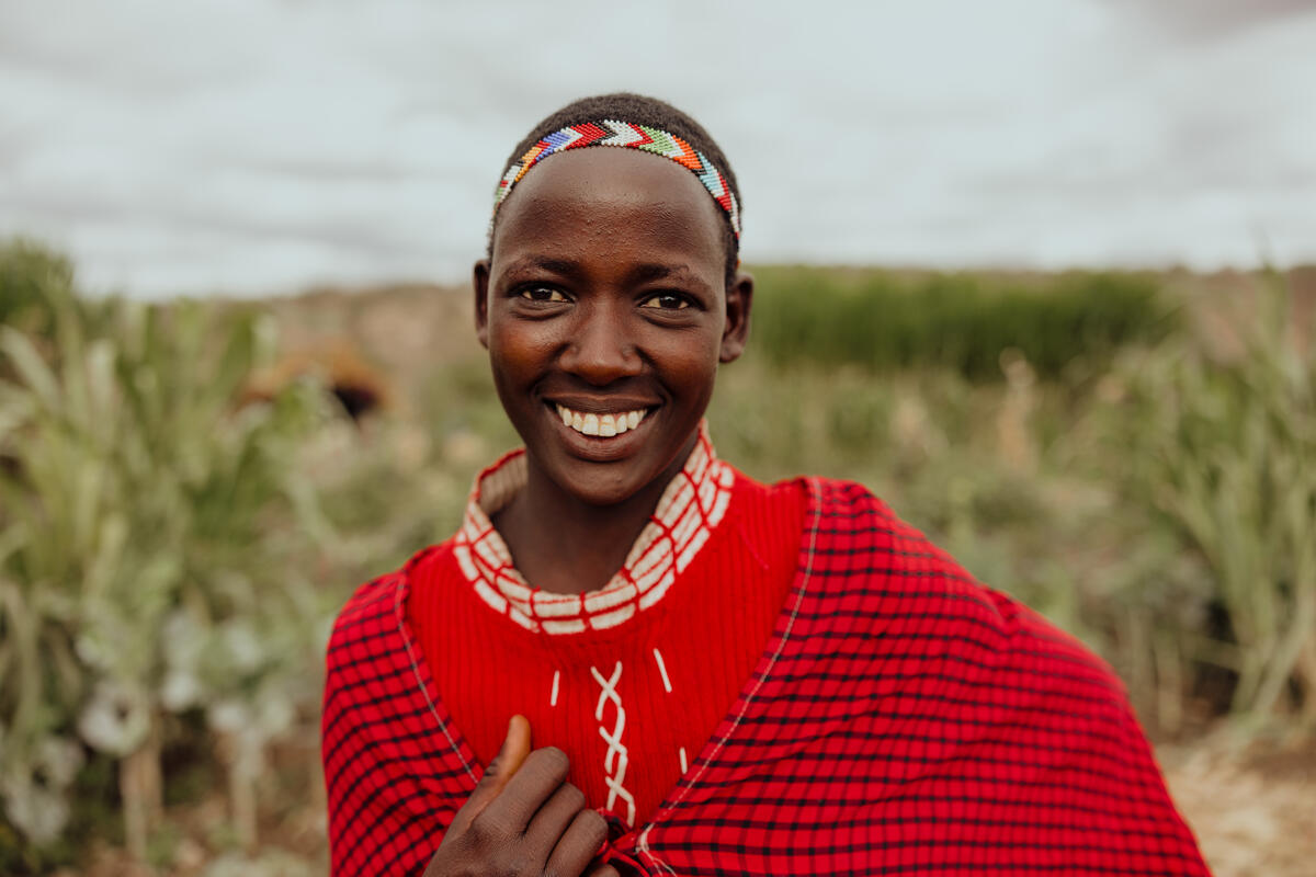 A young boy smiles in field in Kenya