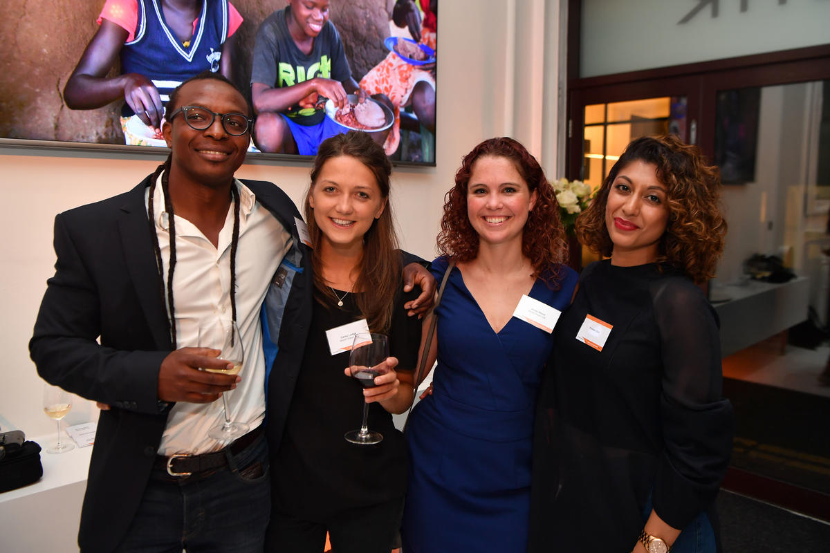4 people in the UK smile as they stand together at an event
