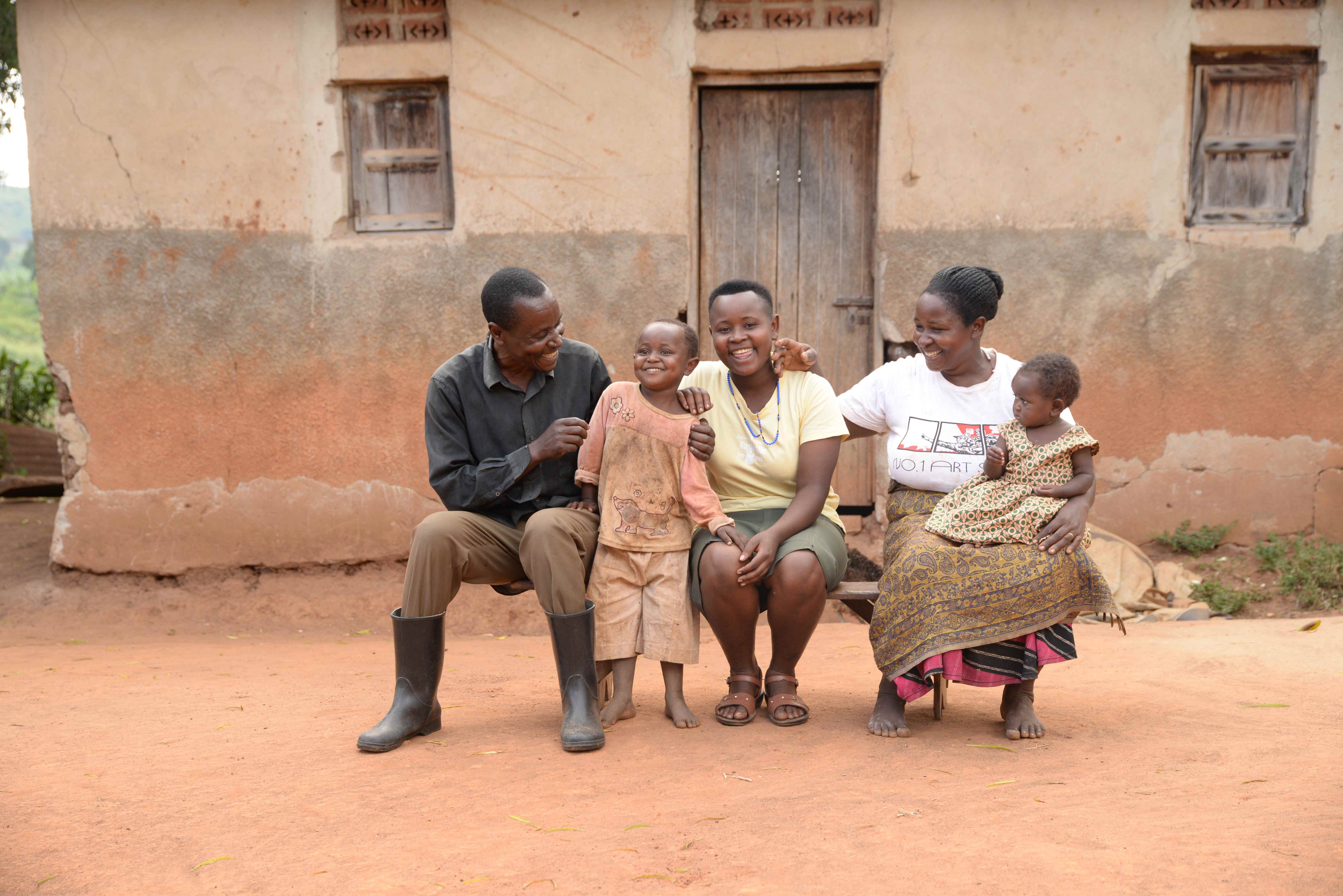 Juliet sits on a bench in front of her home, surrounded by her family