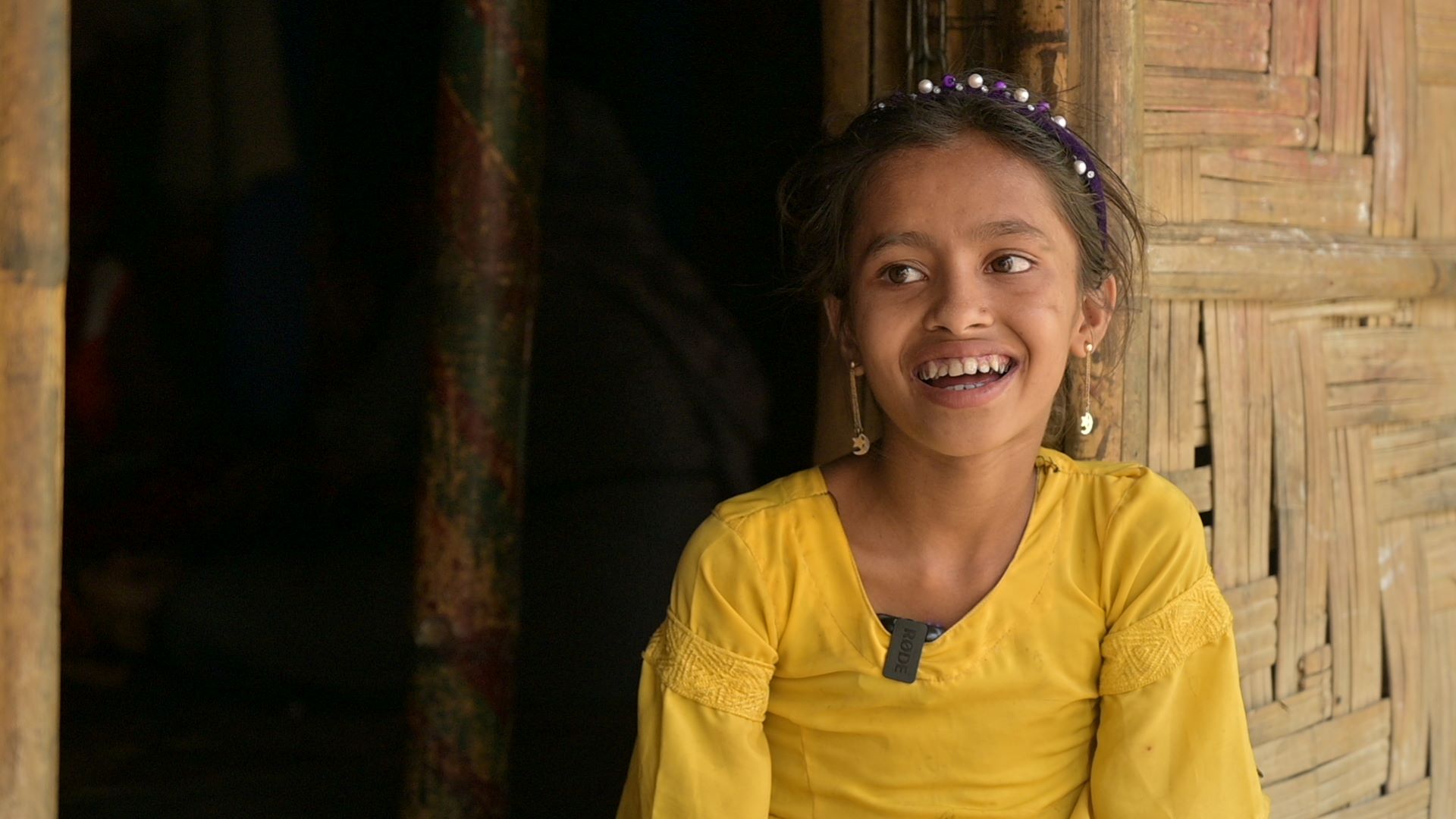 Rohingya refugee girl dressed in yellow and smiling