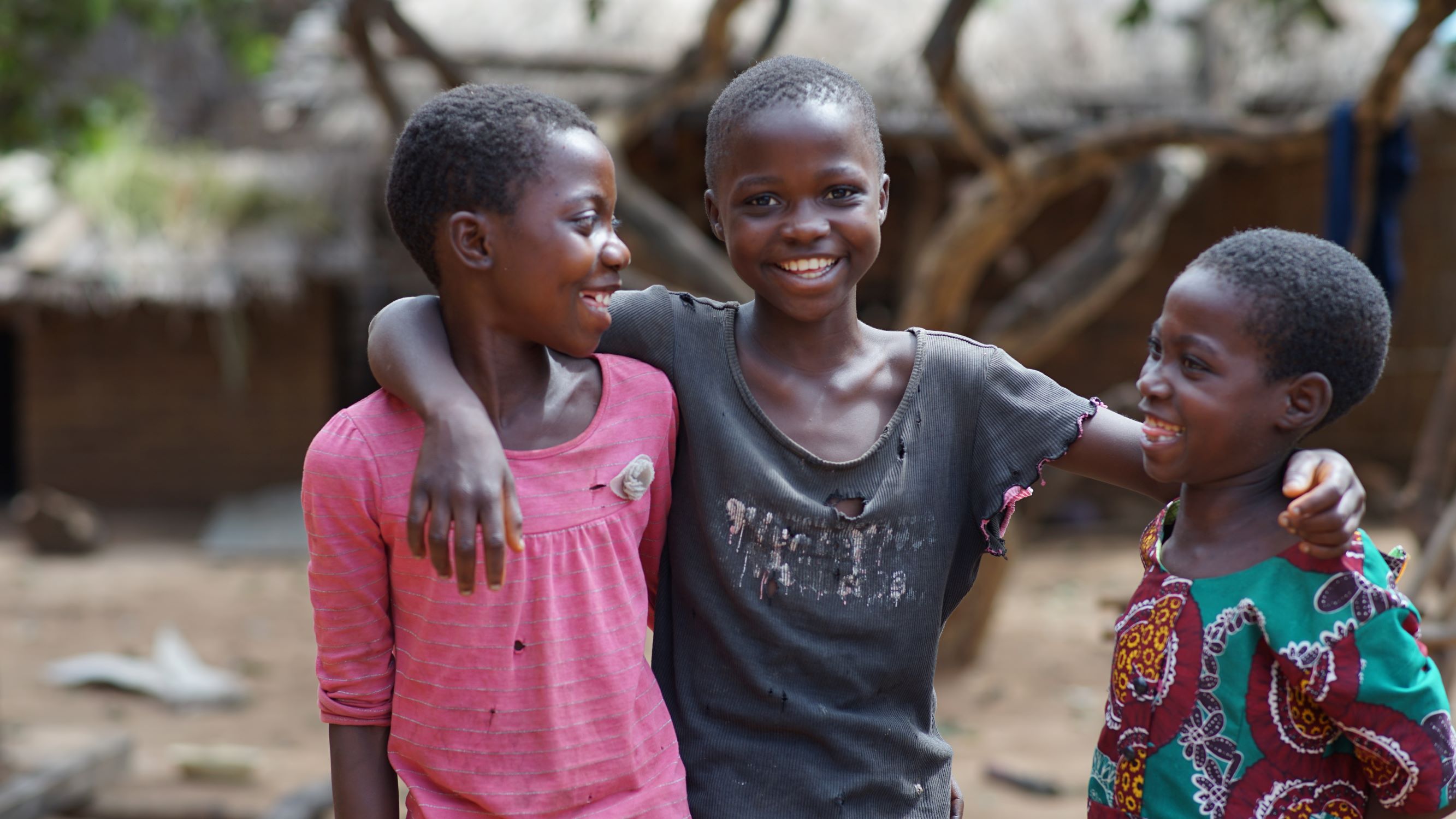 Three children smile and play in Malawi
