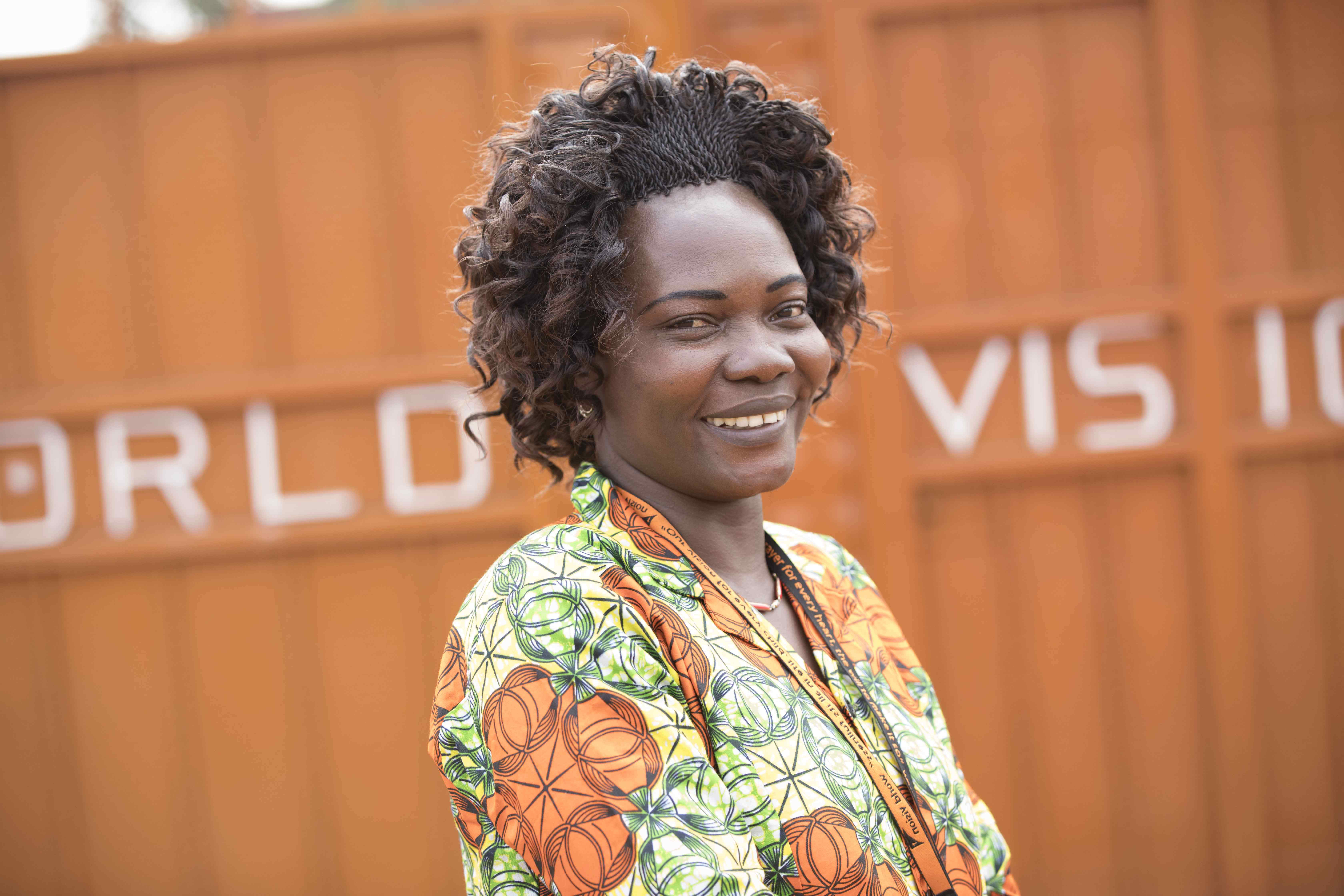 World Vision aid worker in South Sudan smiles, wearing a green and orange top
