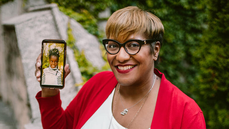 Woman in the US smiles as she looks at picture of the child she sponsors