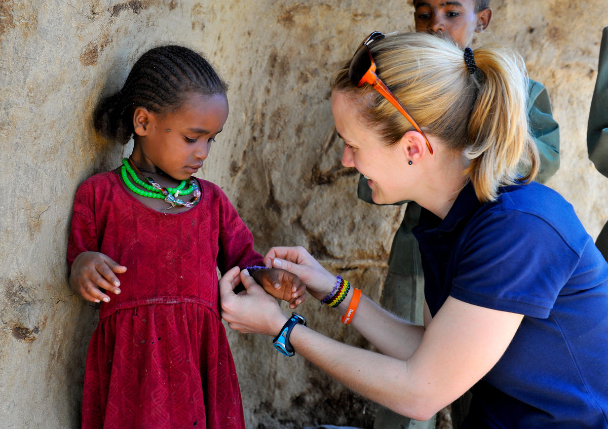 A child sponsor, gives a child a necklace and bracelet matching her own, in Ethopia