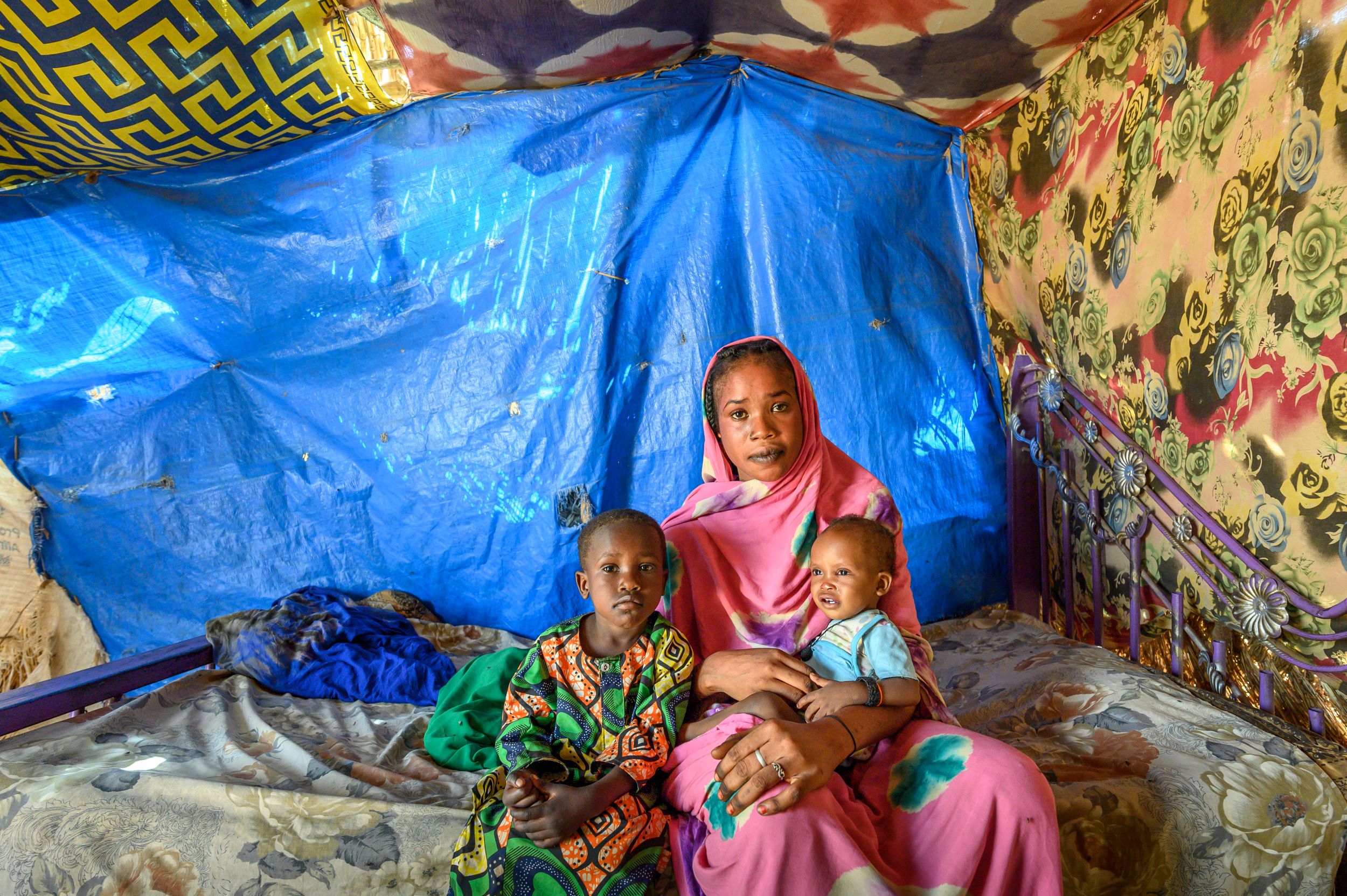 Refugee family, mother, baby and child, inside their tent