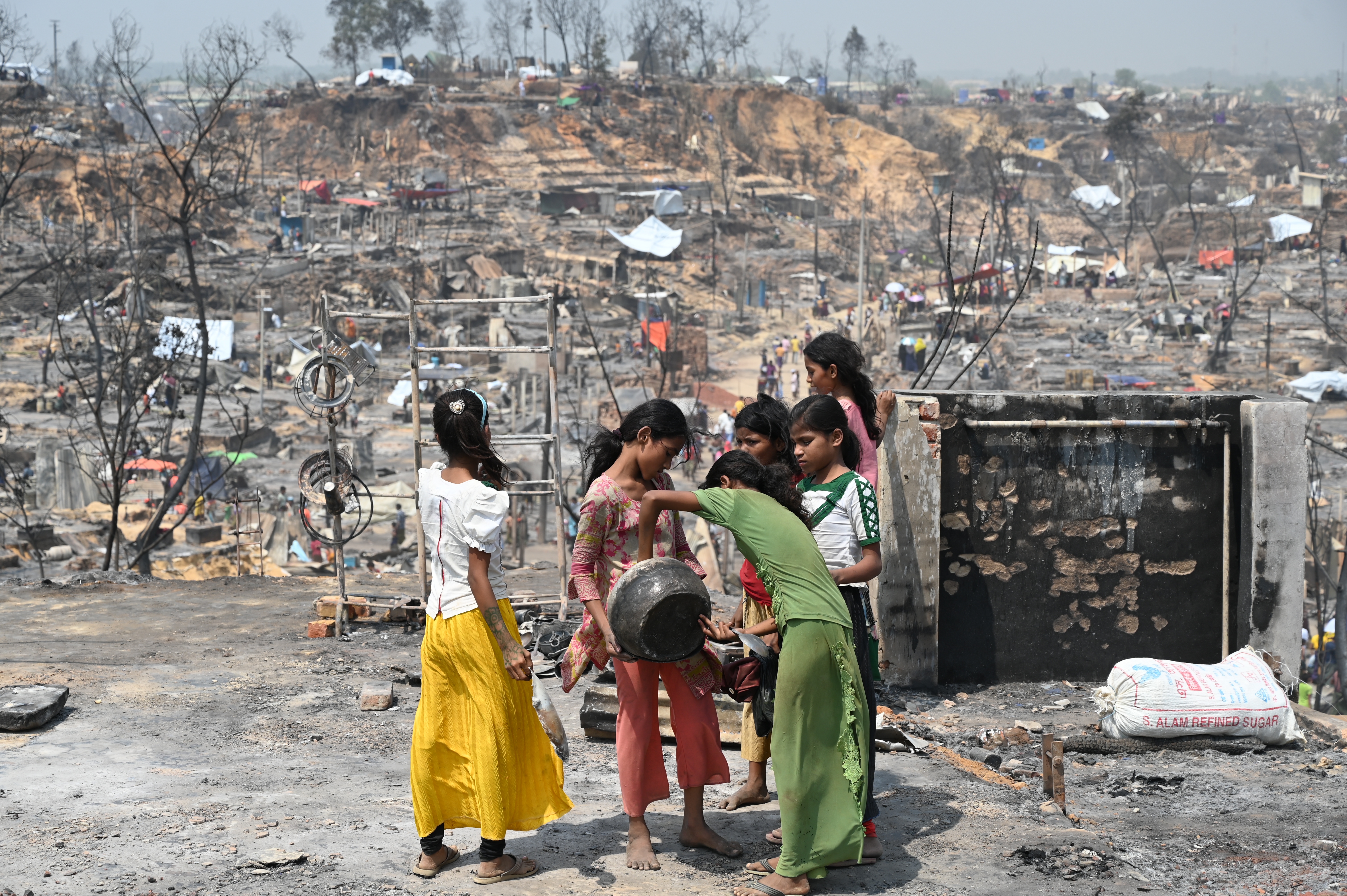 Young women are looking for what they can salvage after a fire swept through the refugee camp in March 2021.