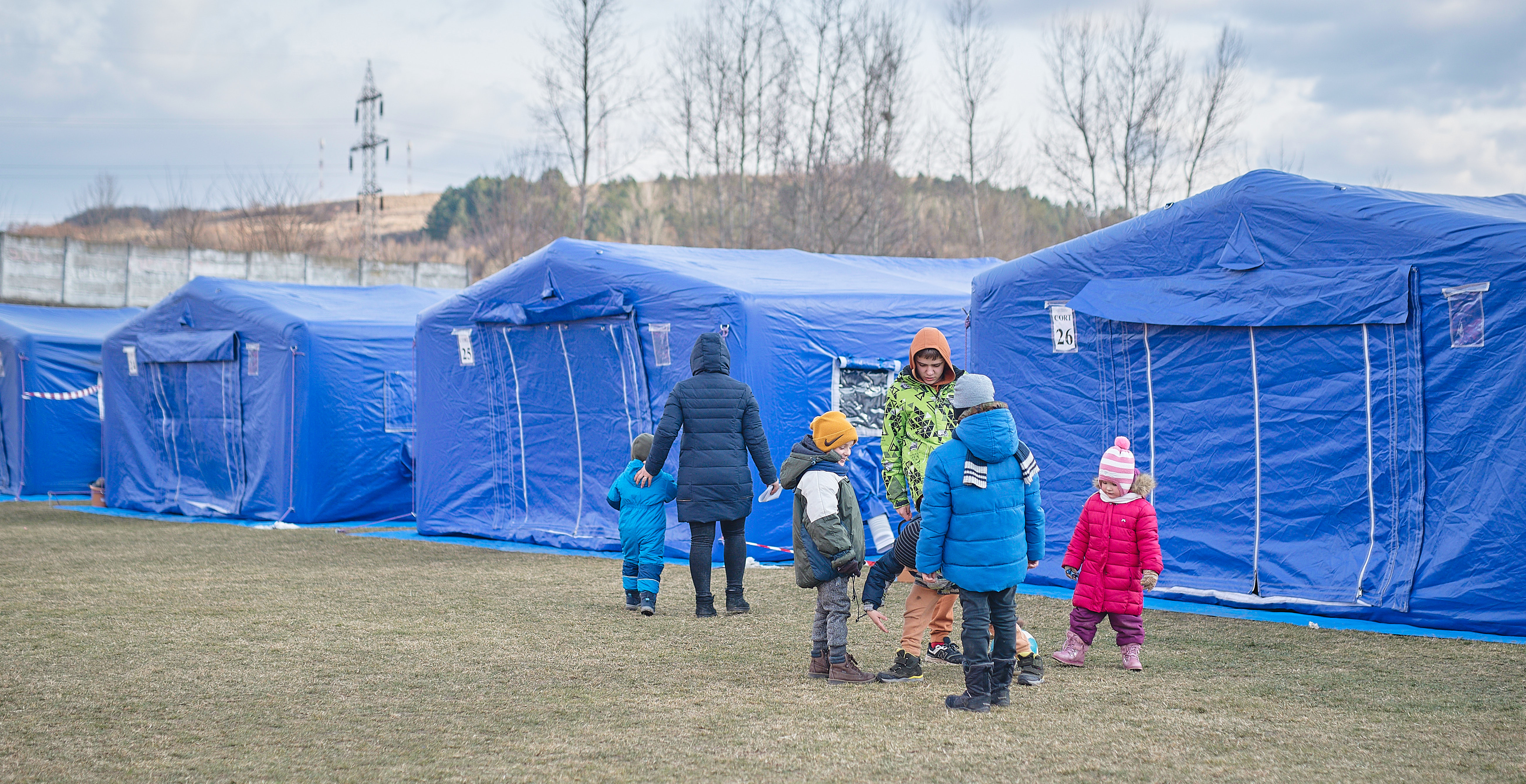 A family stands in front Refugee tents for sleeping, near the border.