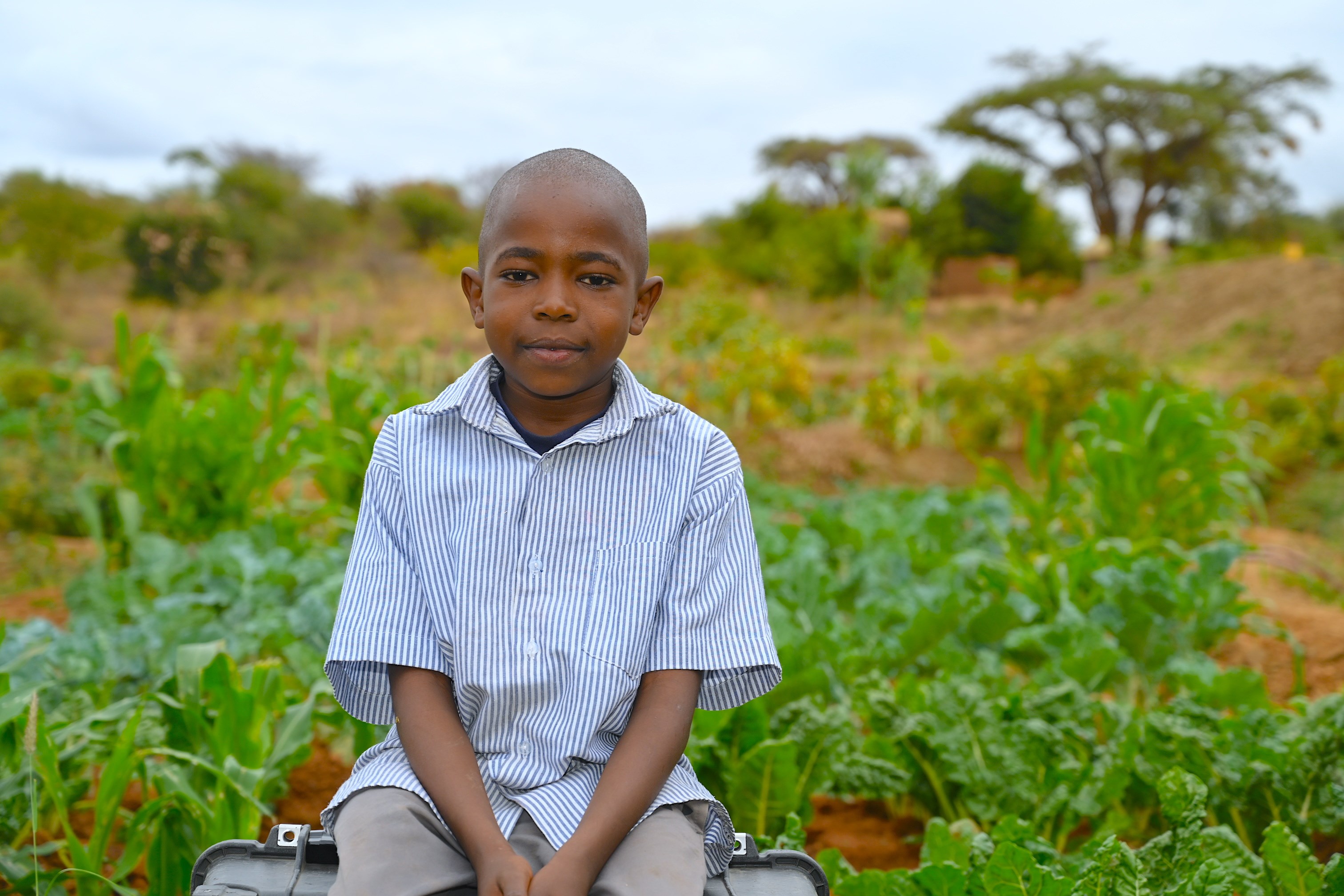 Joshua sitting next to the family's crops