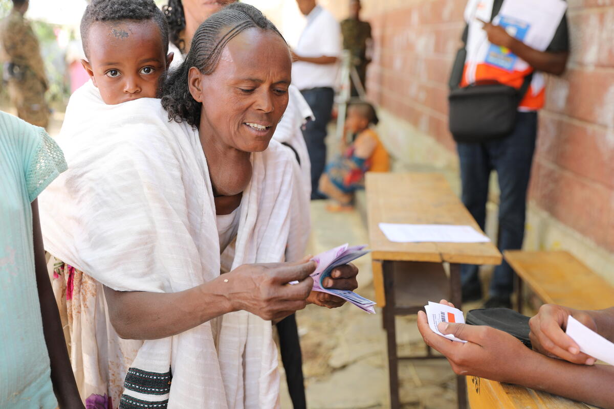 A refugee woman collects her cash voucher from World Vision relief worker. 