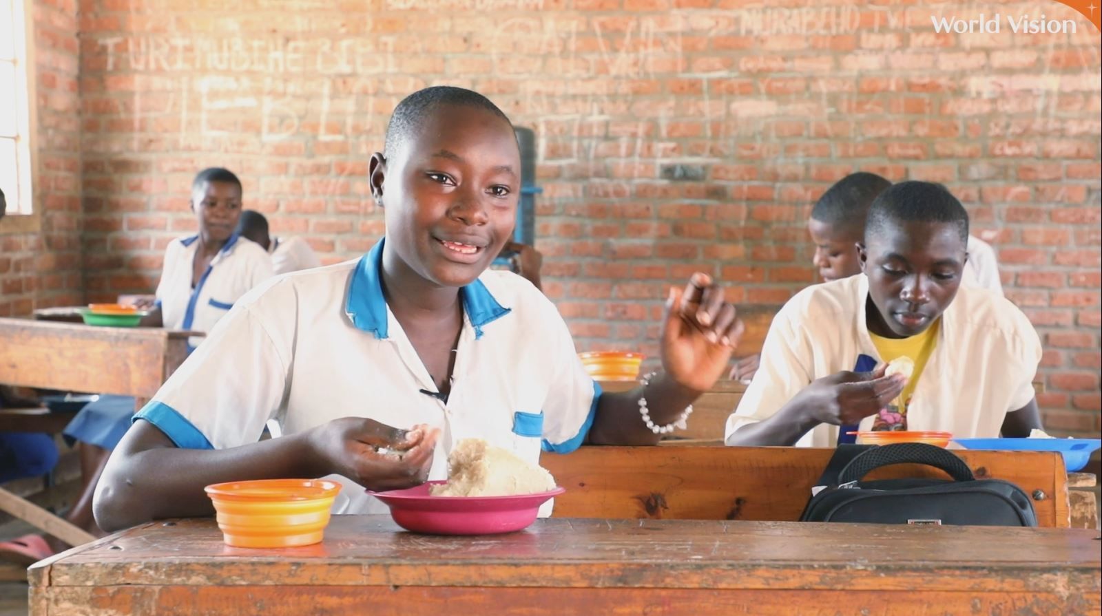 Smiling students sit to enjoy their hot school meals in Burundi