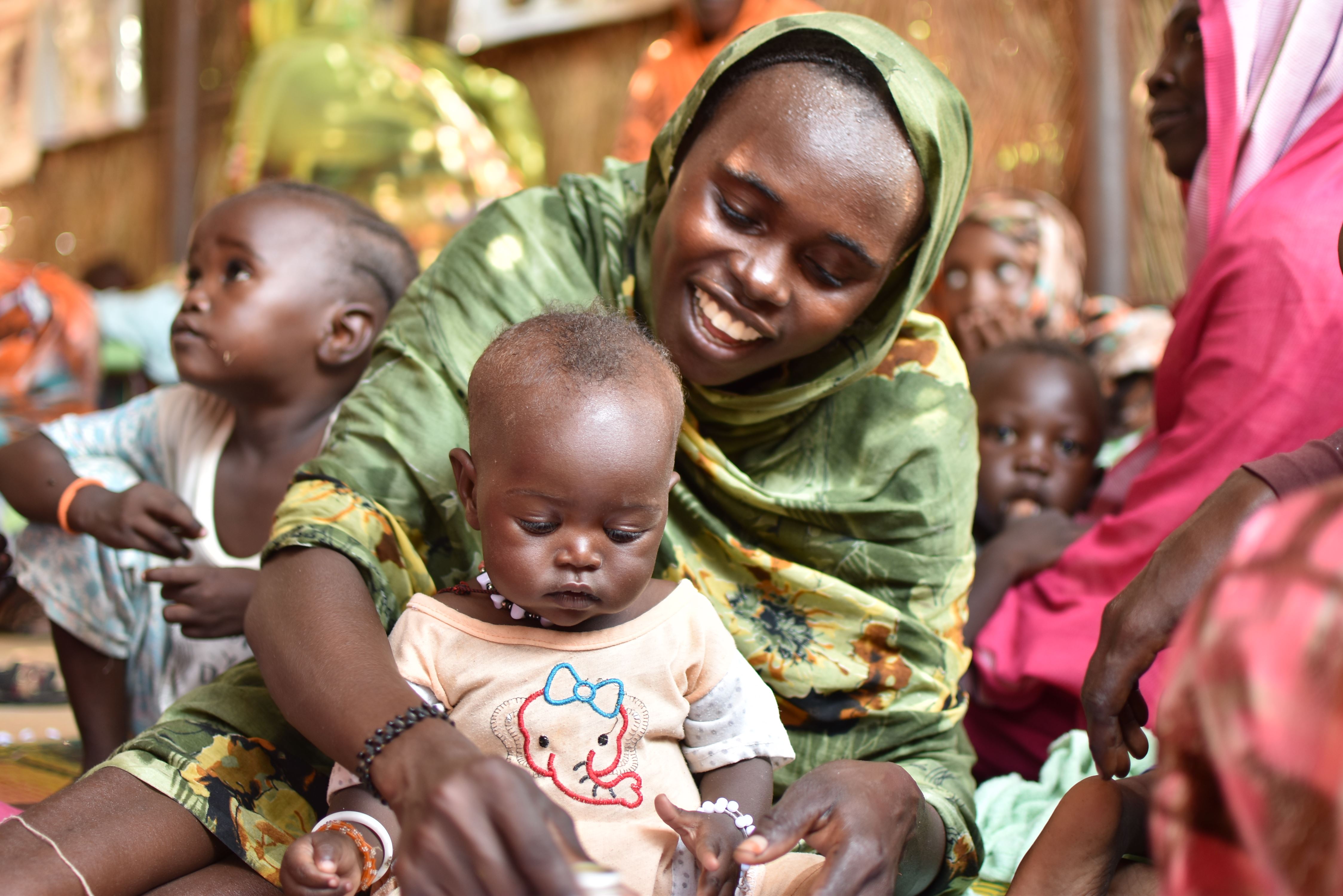 Woman smiles as she plays with her daughter, who is now recovered from malnutrition and is a healthy weight after World Vision's support in Sudan