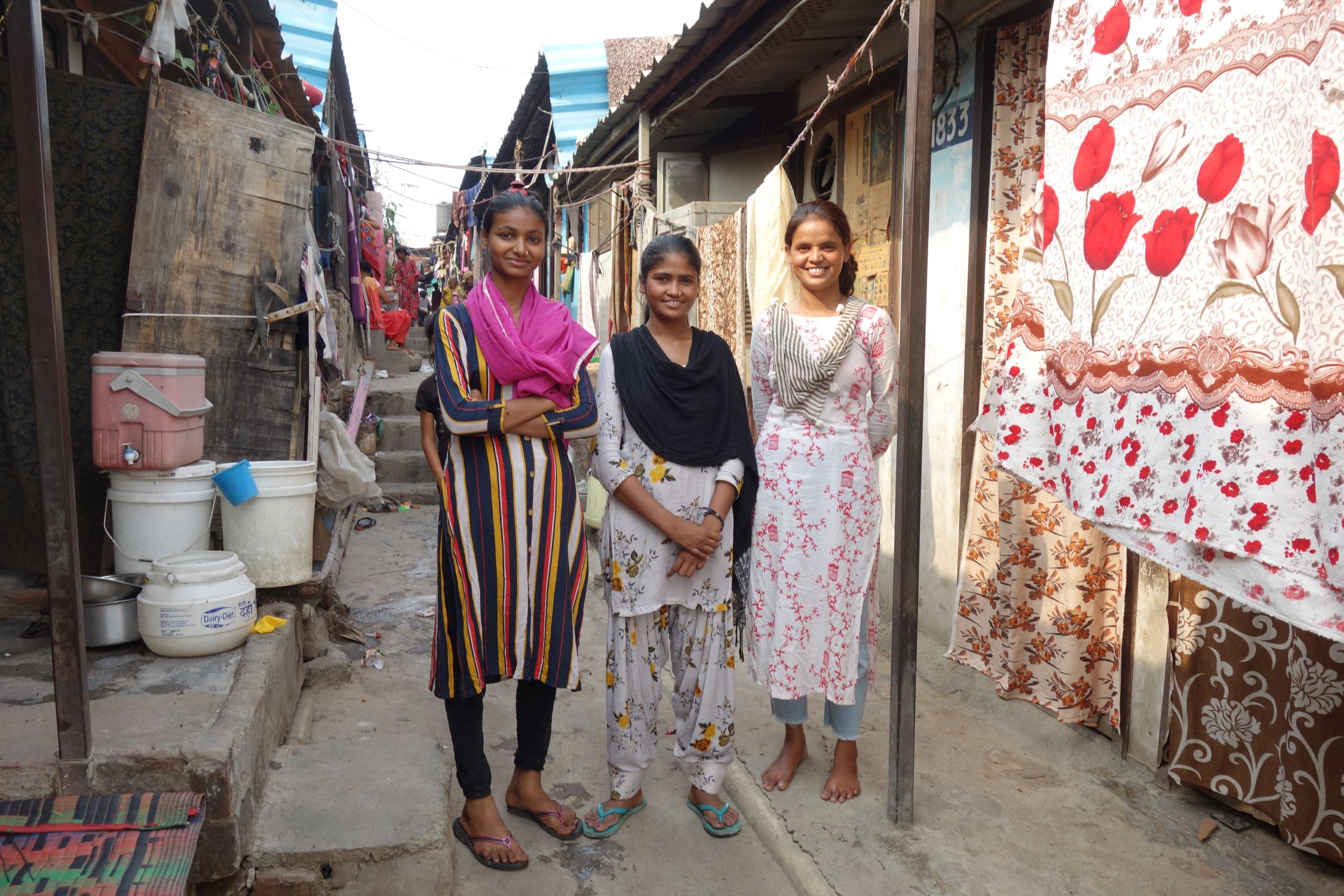 Three teen girls in India standing in the transit camp