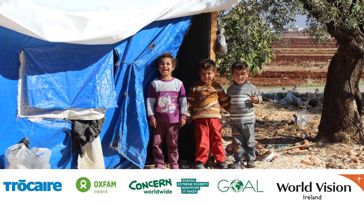 Boy in Venezuela sits in a cemetery, looking into the camera wearing a red top