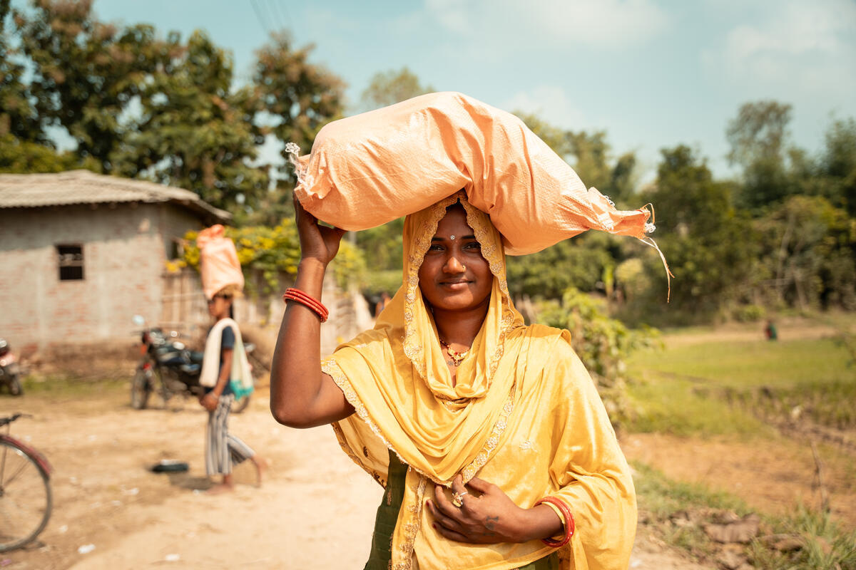 Mother in Nepal carries a big bag of food supplies for her family.