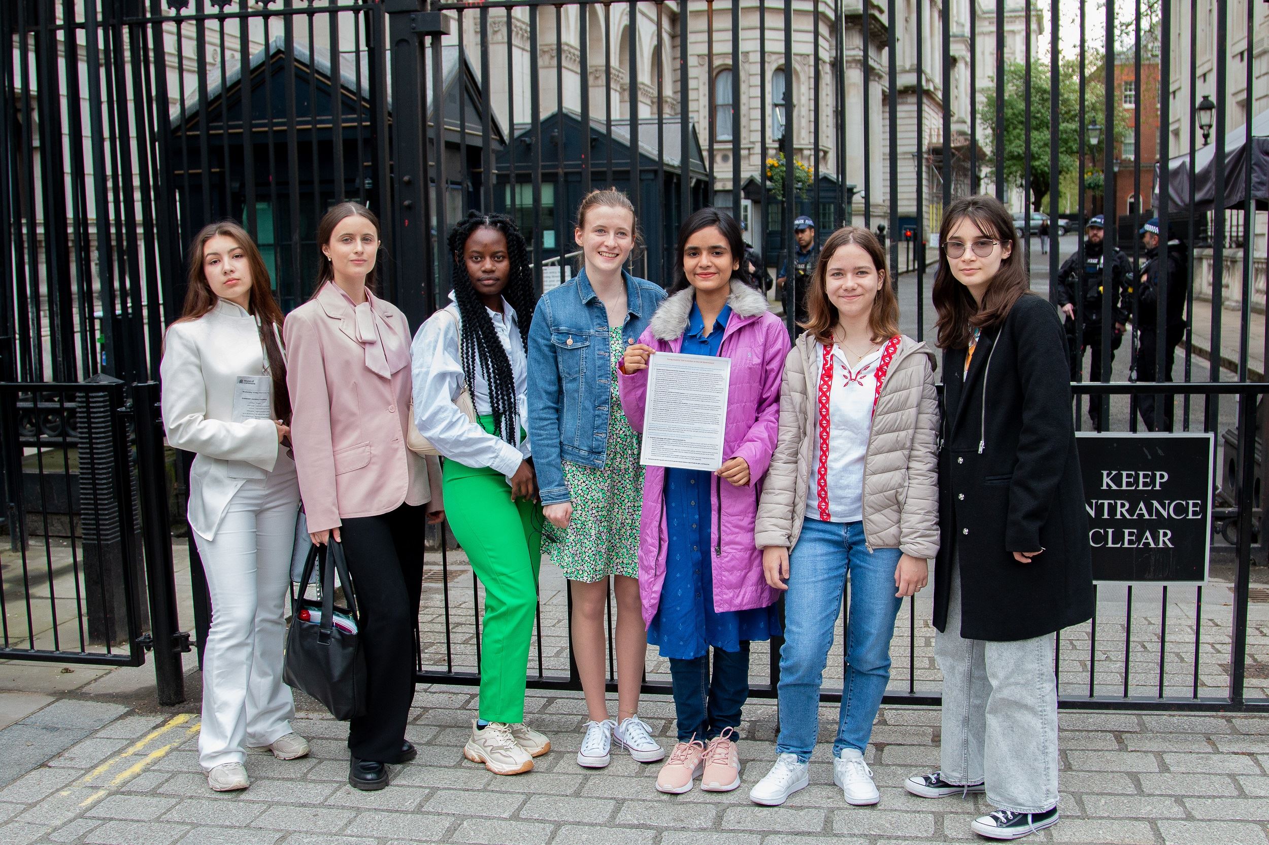 Five young people from Bangladesh, Kenya, Ukraine and the UK stand outside the gates to Downing Street, London