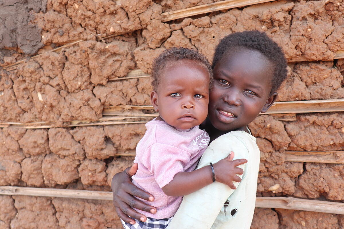 Former child solider stands in a field in South Sudan, his face shielded.