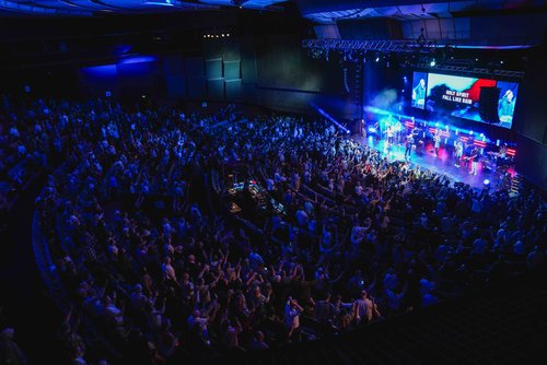 An aerial shot of a conference with the stage and screens visible. 