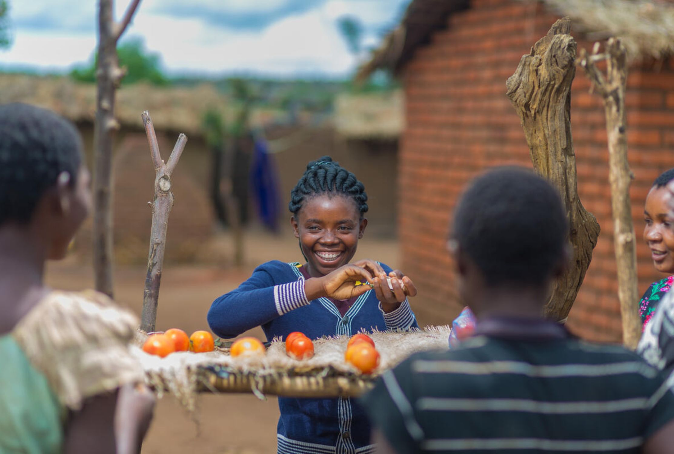 Girl smiles as she sells tomatoes to generate an income in Malawi