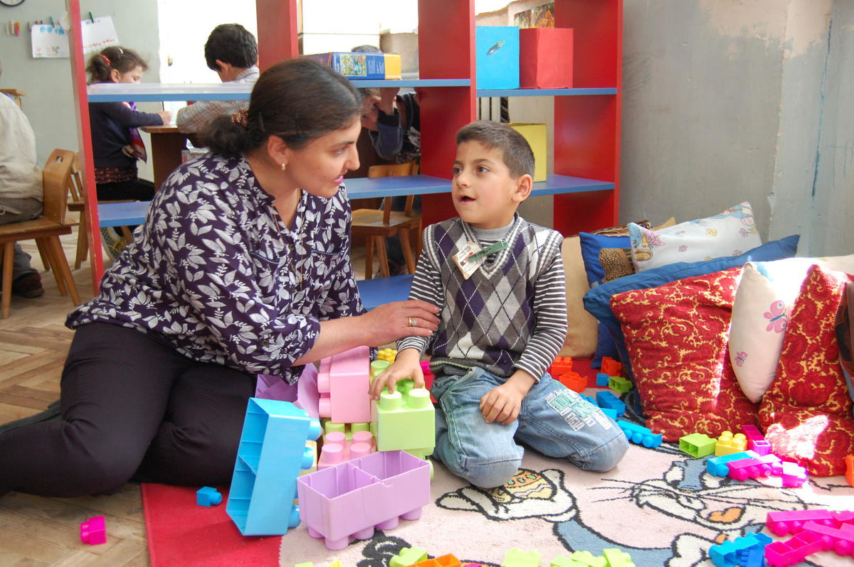 A woman sits and plays with a boy at a kindergarten in Georgia that is inclusive to children with disabilities