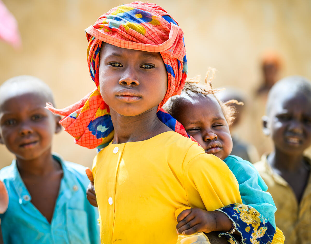 Hafisa, 8, a Sudanese refugee girl carrying a baby on her back at a World Vision Child-Friendly Space, Chad.