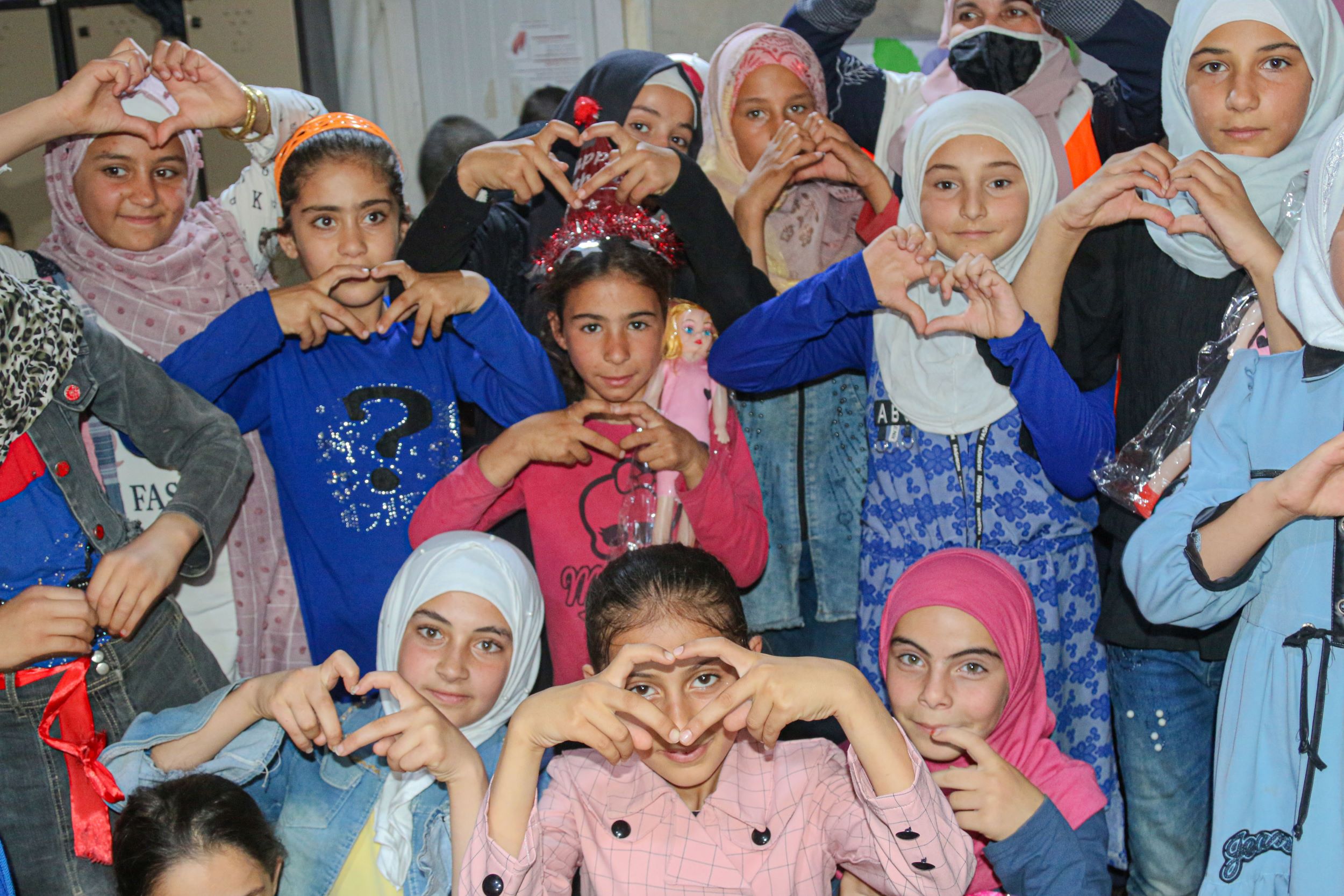 Syrian girls makings hearts shapes with their fingers 
