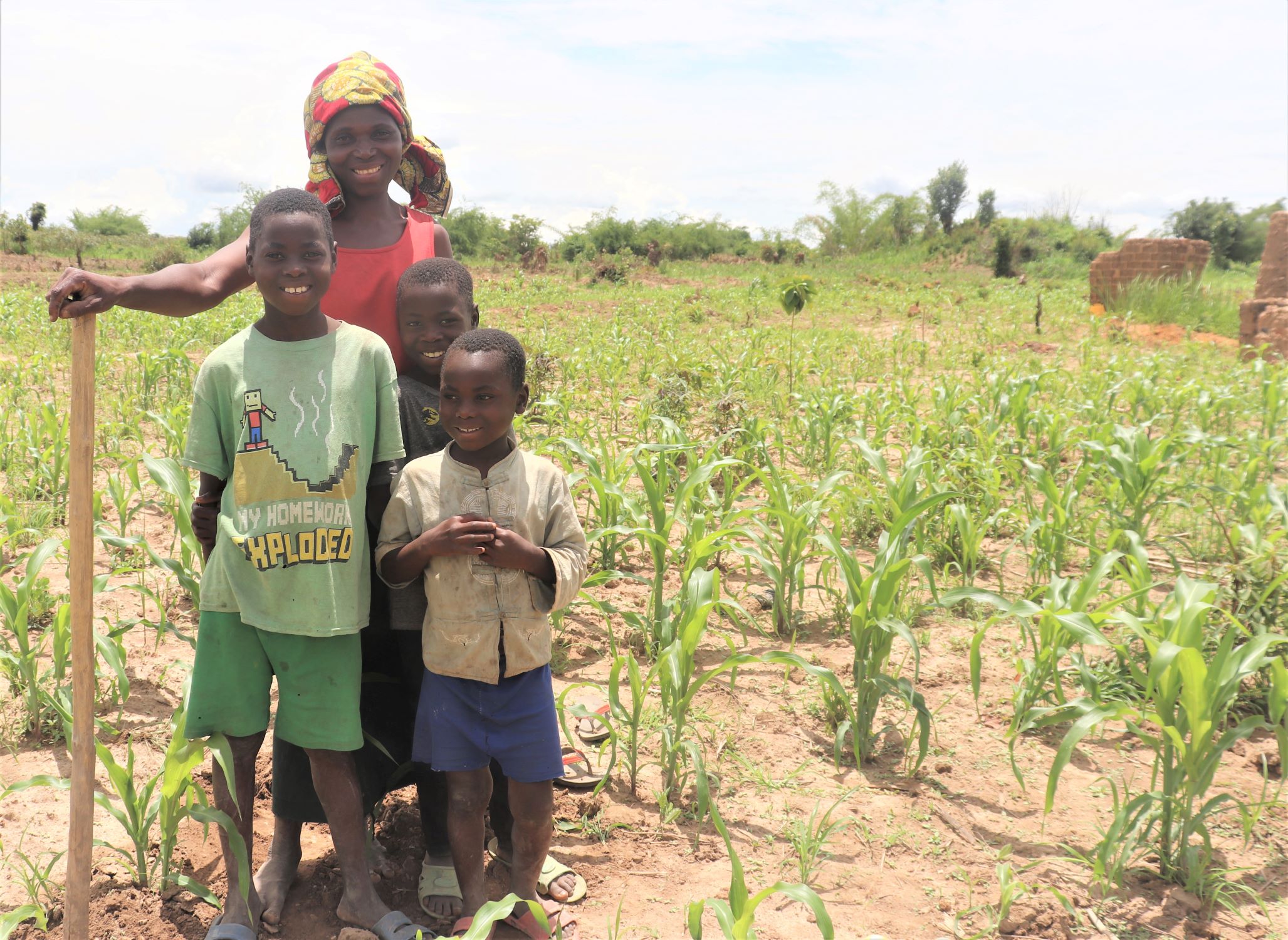 Mother and her three sons in Democratic Republic of Congo smiling by their crops