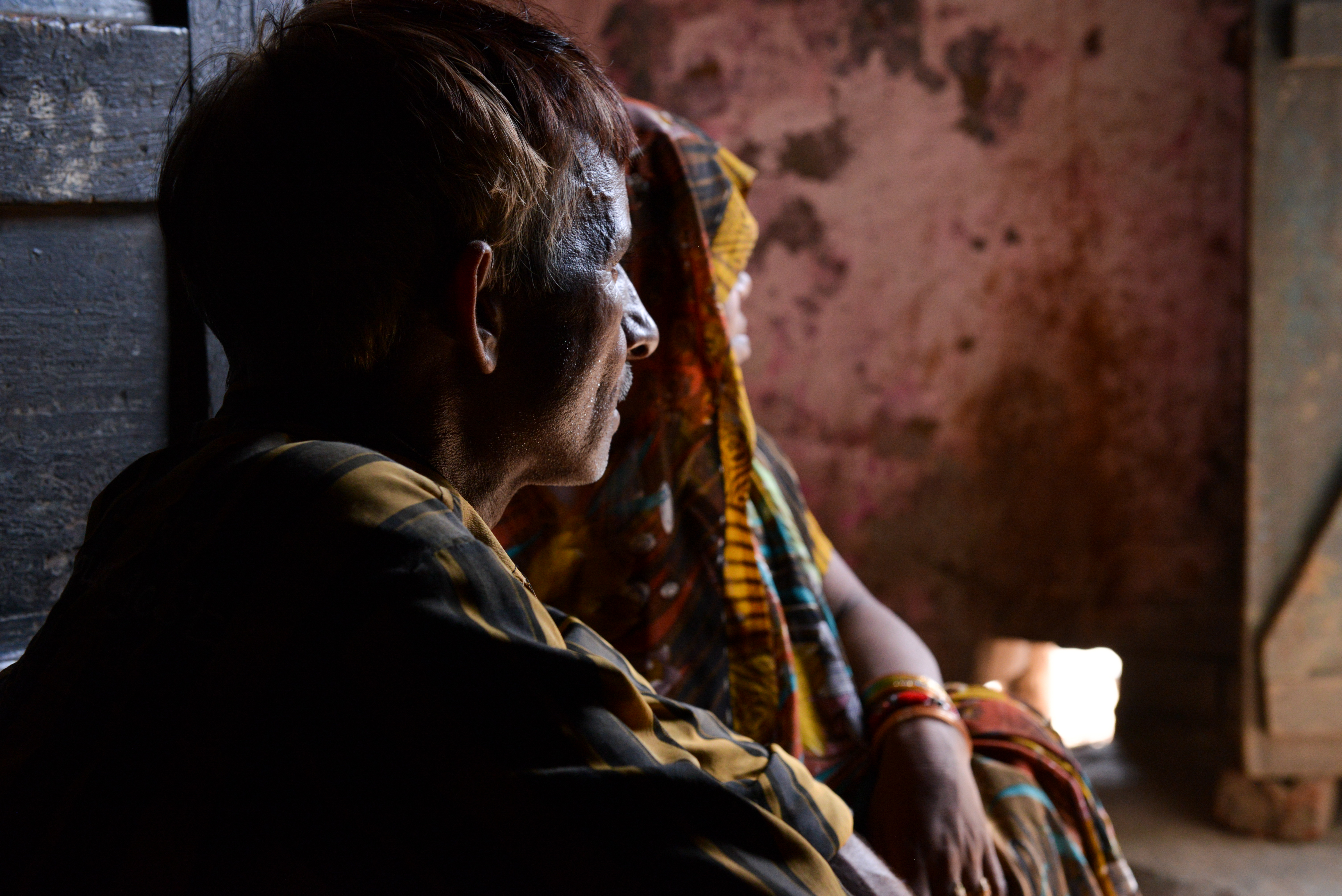 Man and his daughter look away from camera, their faces in shadowd