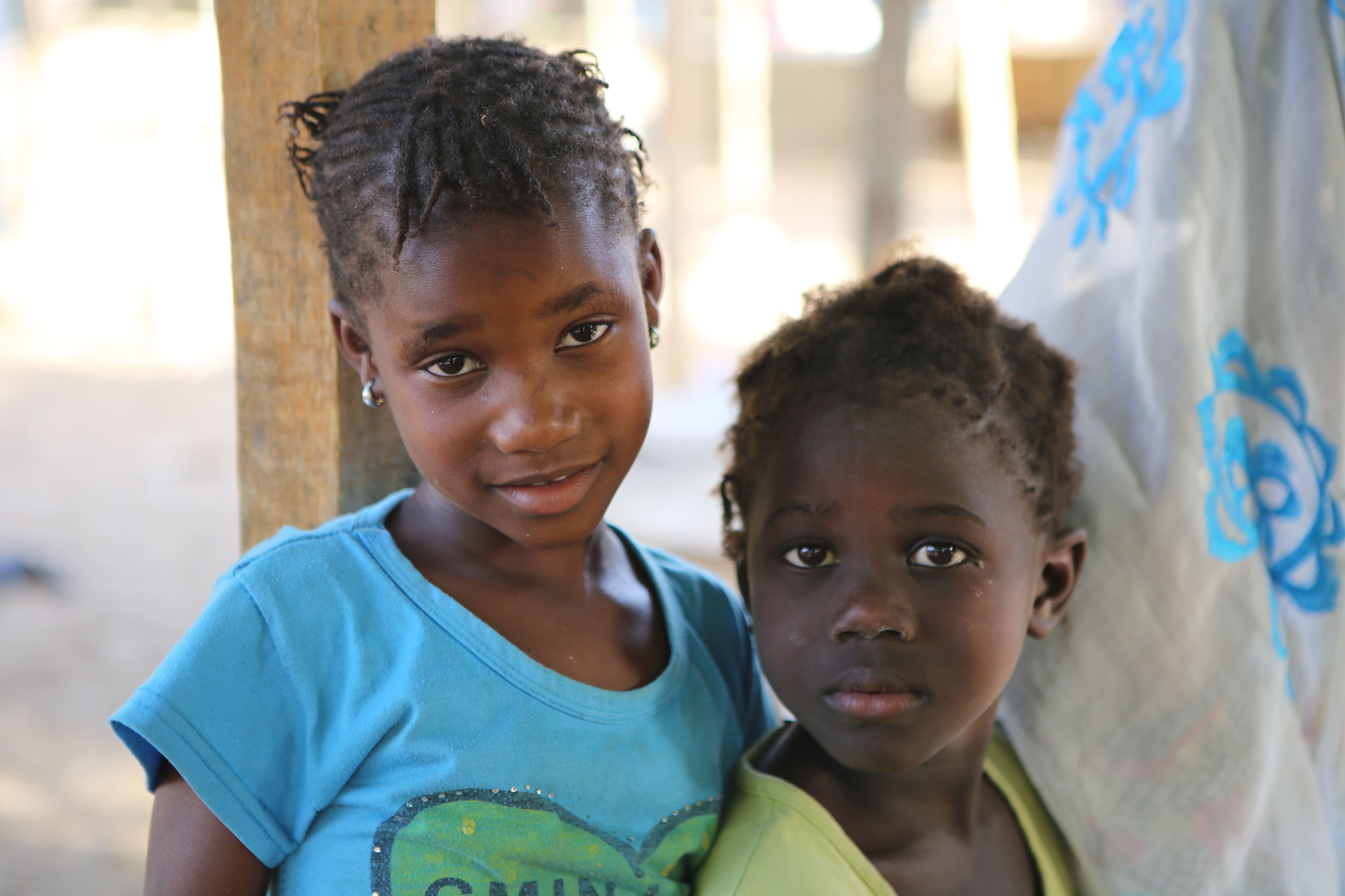 Two children in Senegal look into the camera, one wearing a blue top, one a yellow top