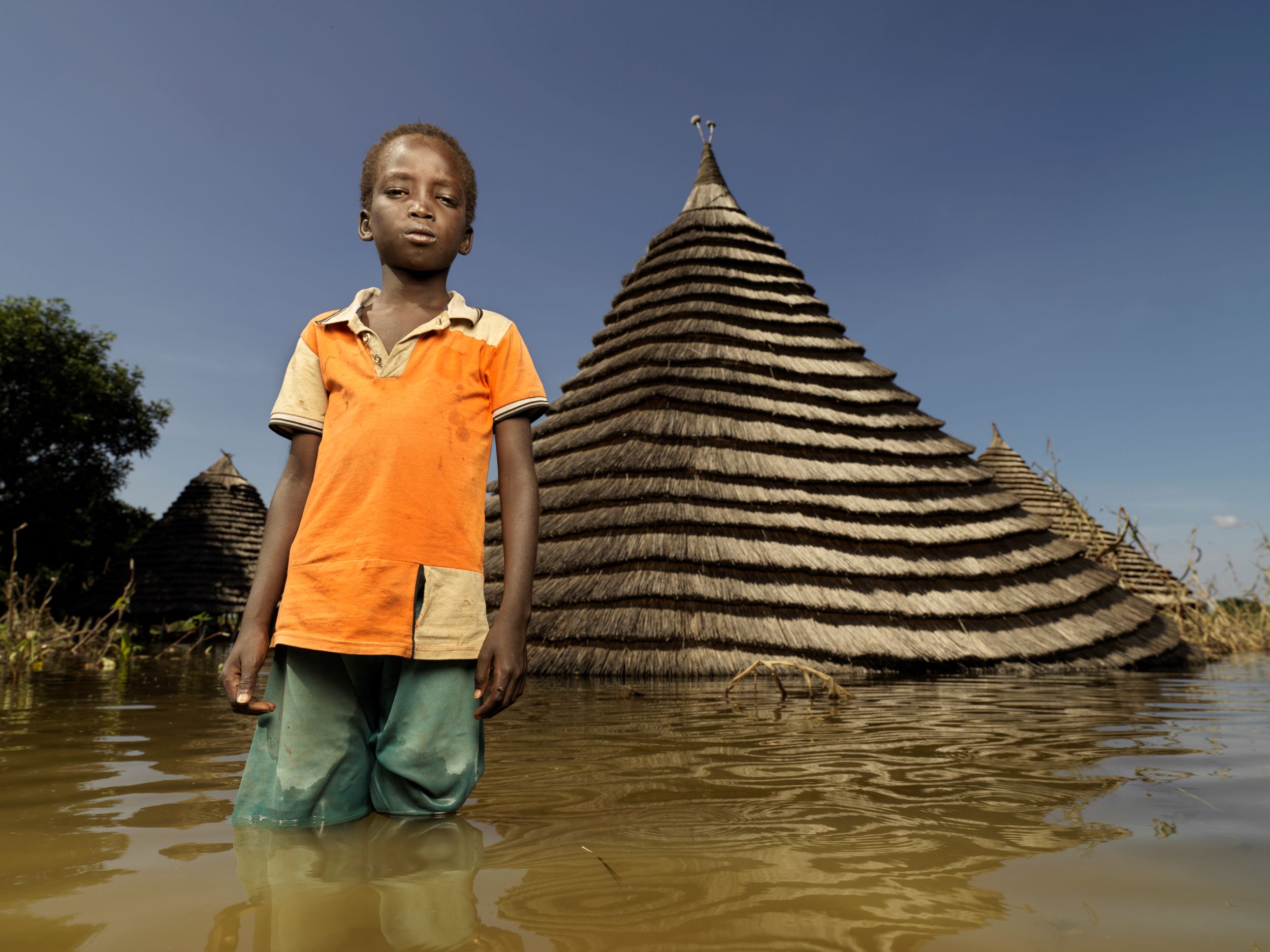 A child stands knee deep in flood waters, South Sudan